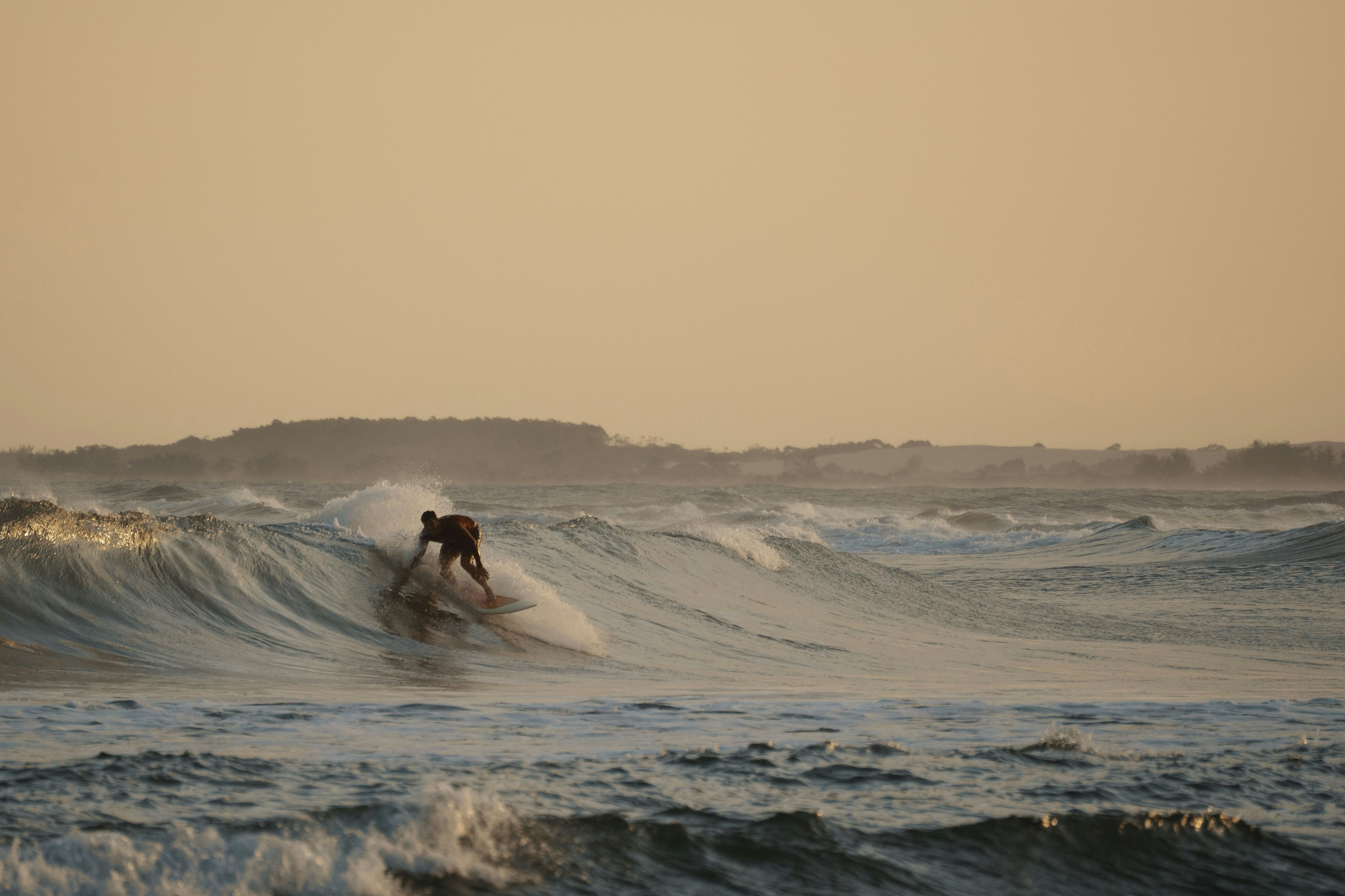 Surfer riding a wave at sunset