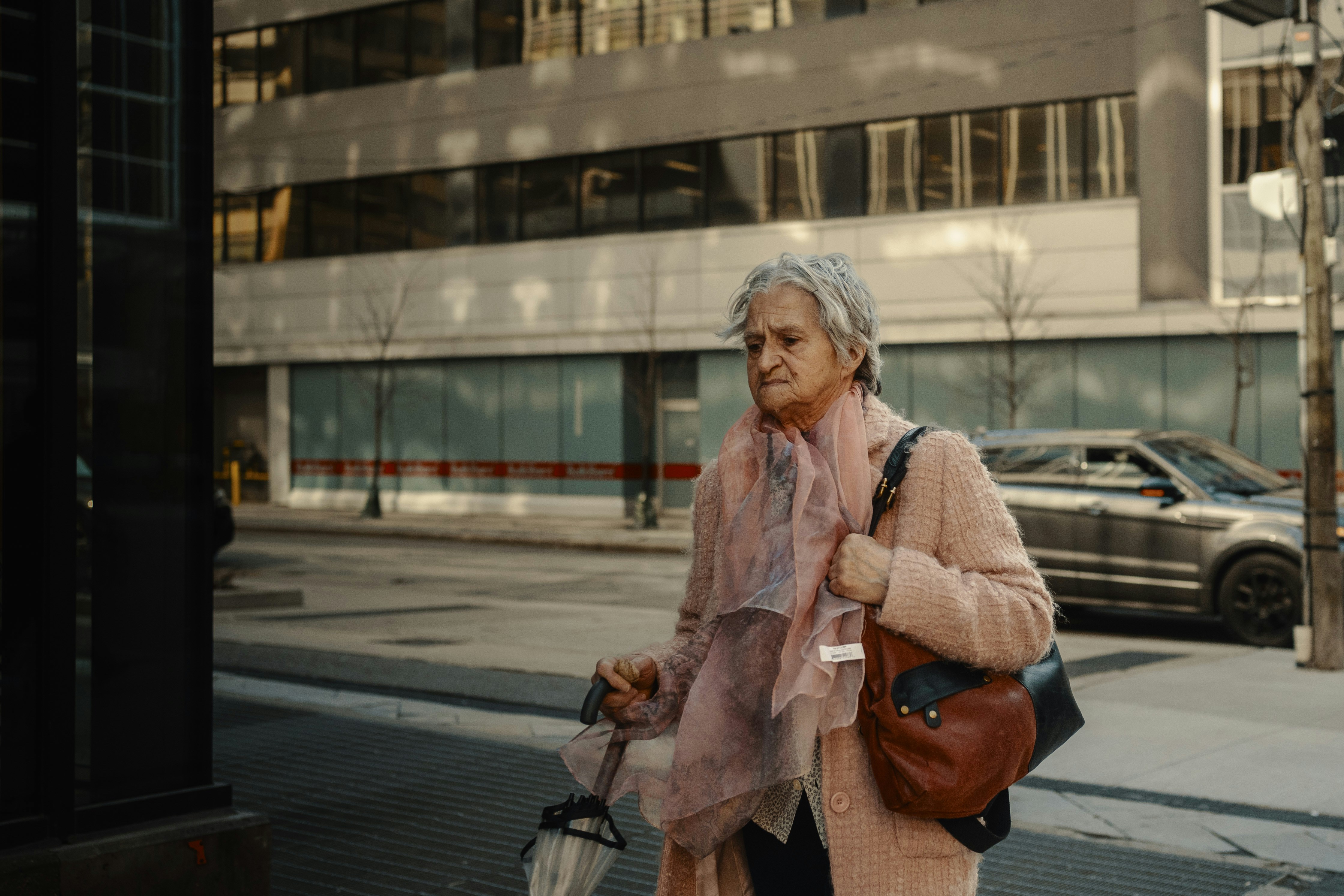 Elderly woman walks down a city street.