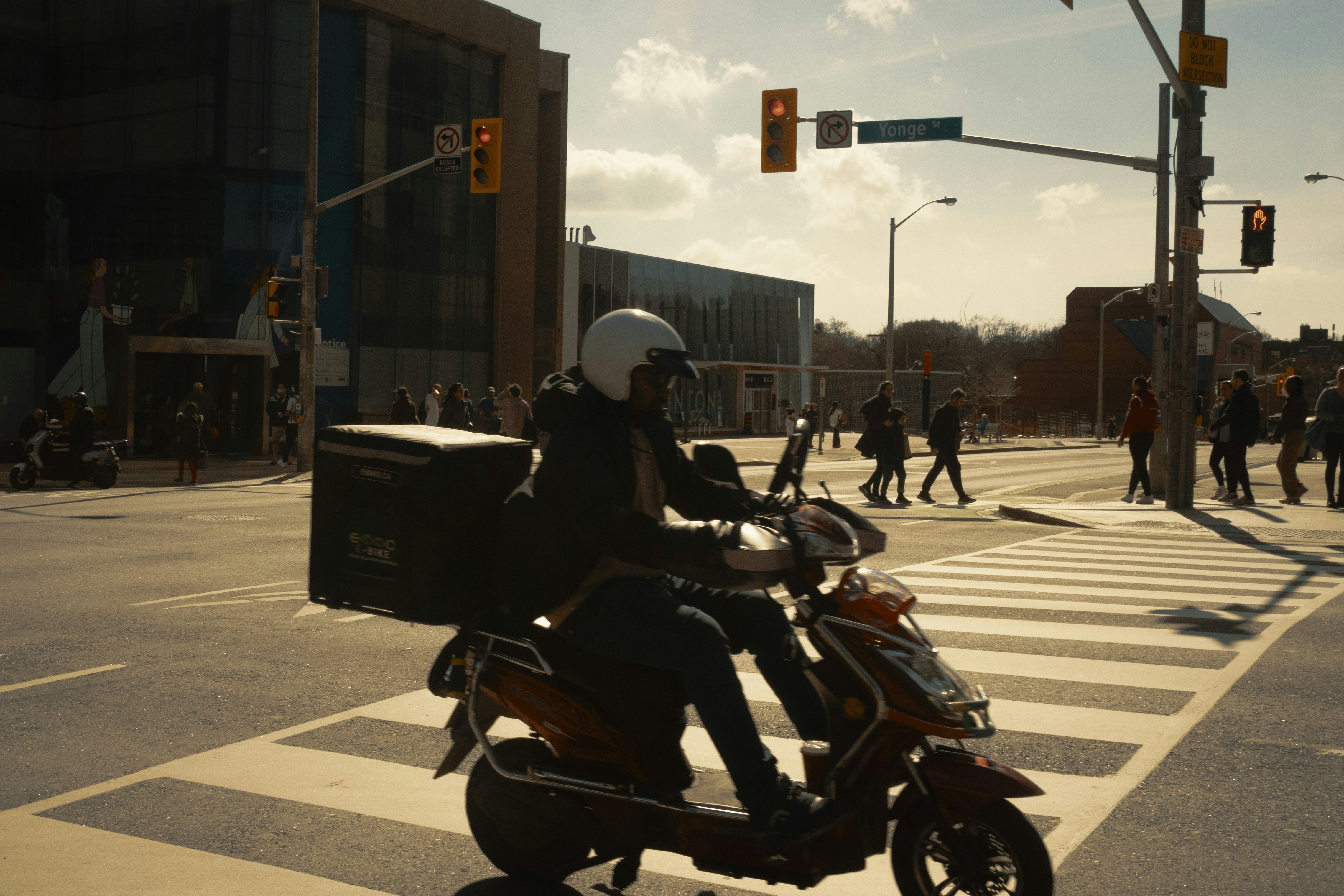 Delivery person on scooter crosses busy street