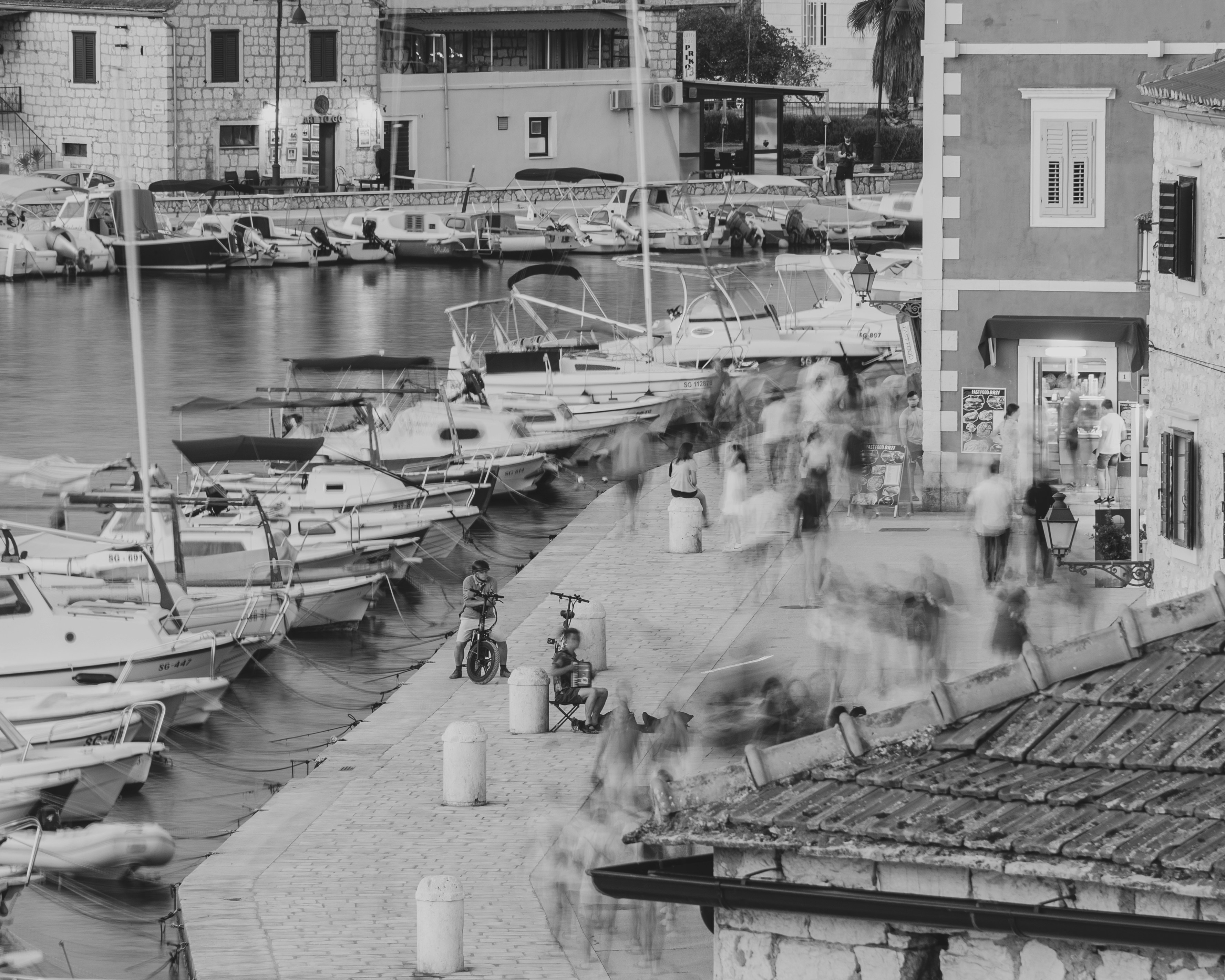 Boats docked in a harbor with people walking by