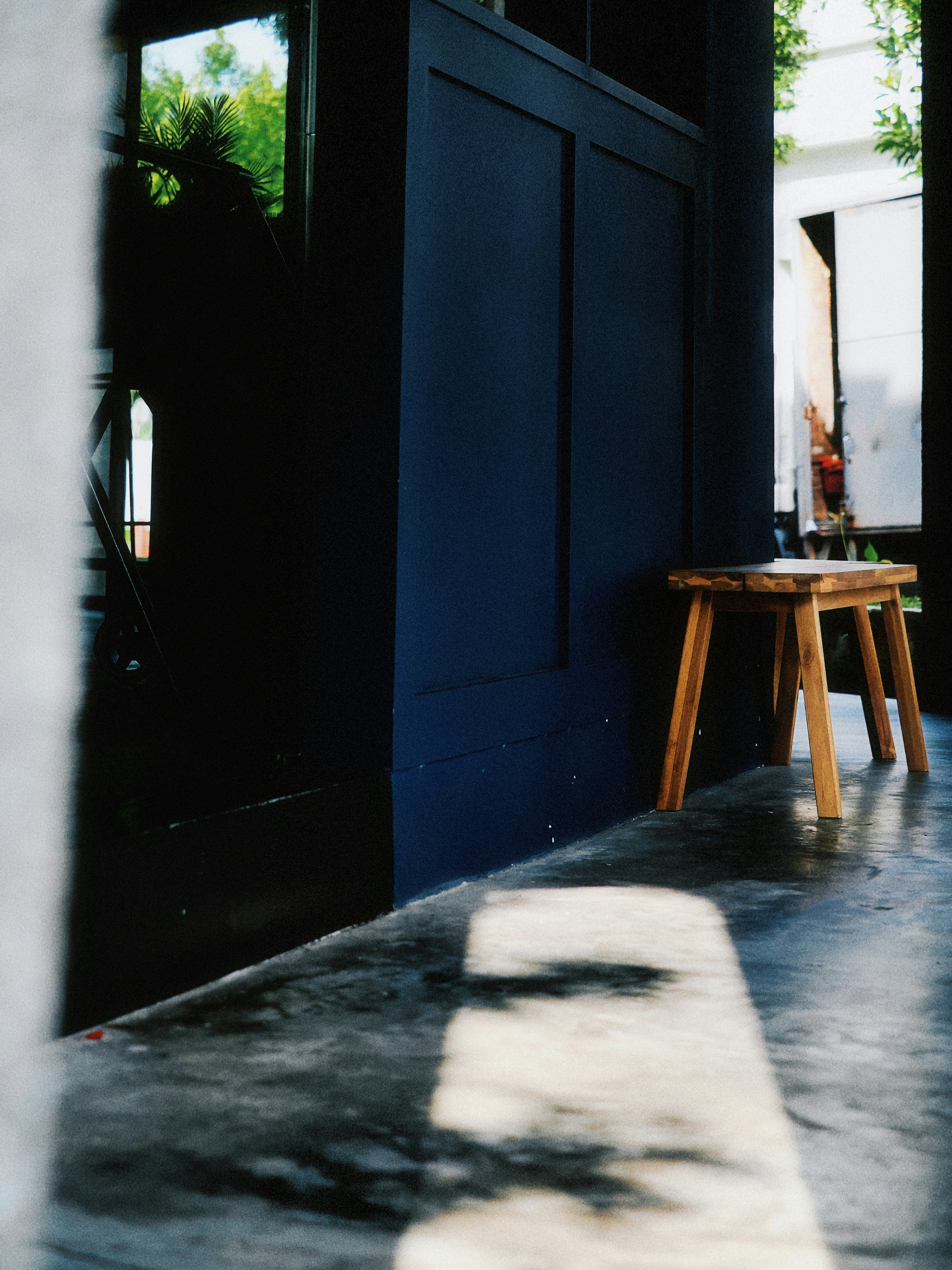 Wooden stool placed by a dark blue wall.