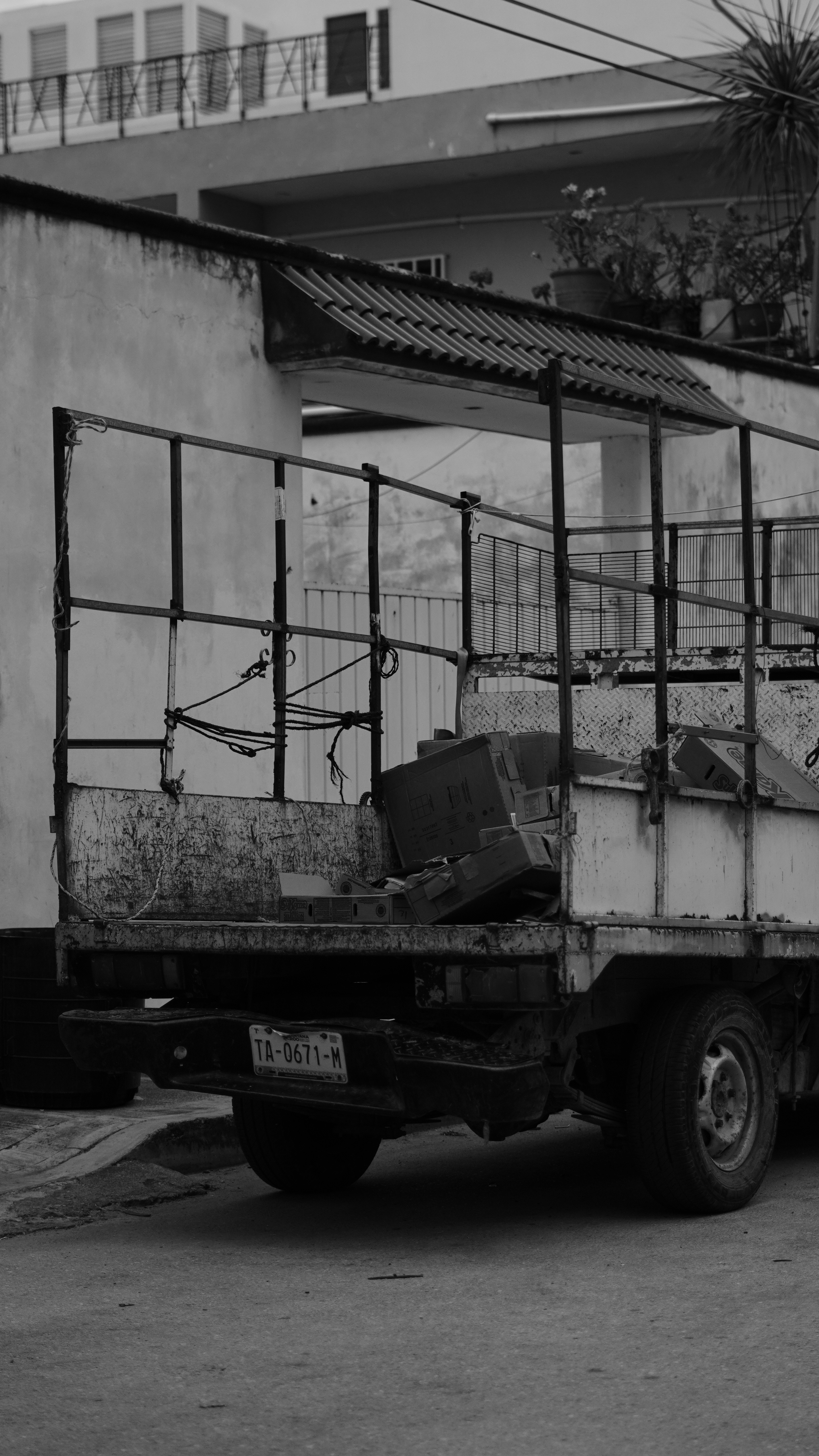 Old flatbed truck loaded with junk in black and white.