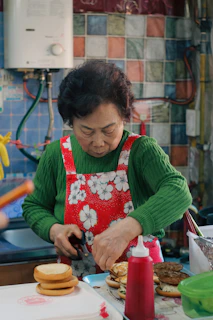 Elderly woman preparing burgers in a kitchen