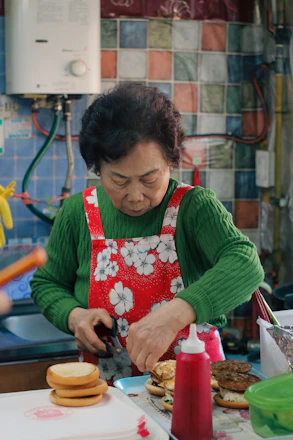 Elderly woman preparing burgers in a kitchen