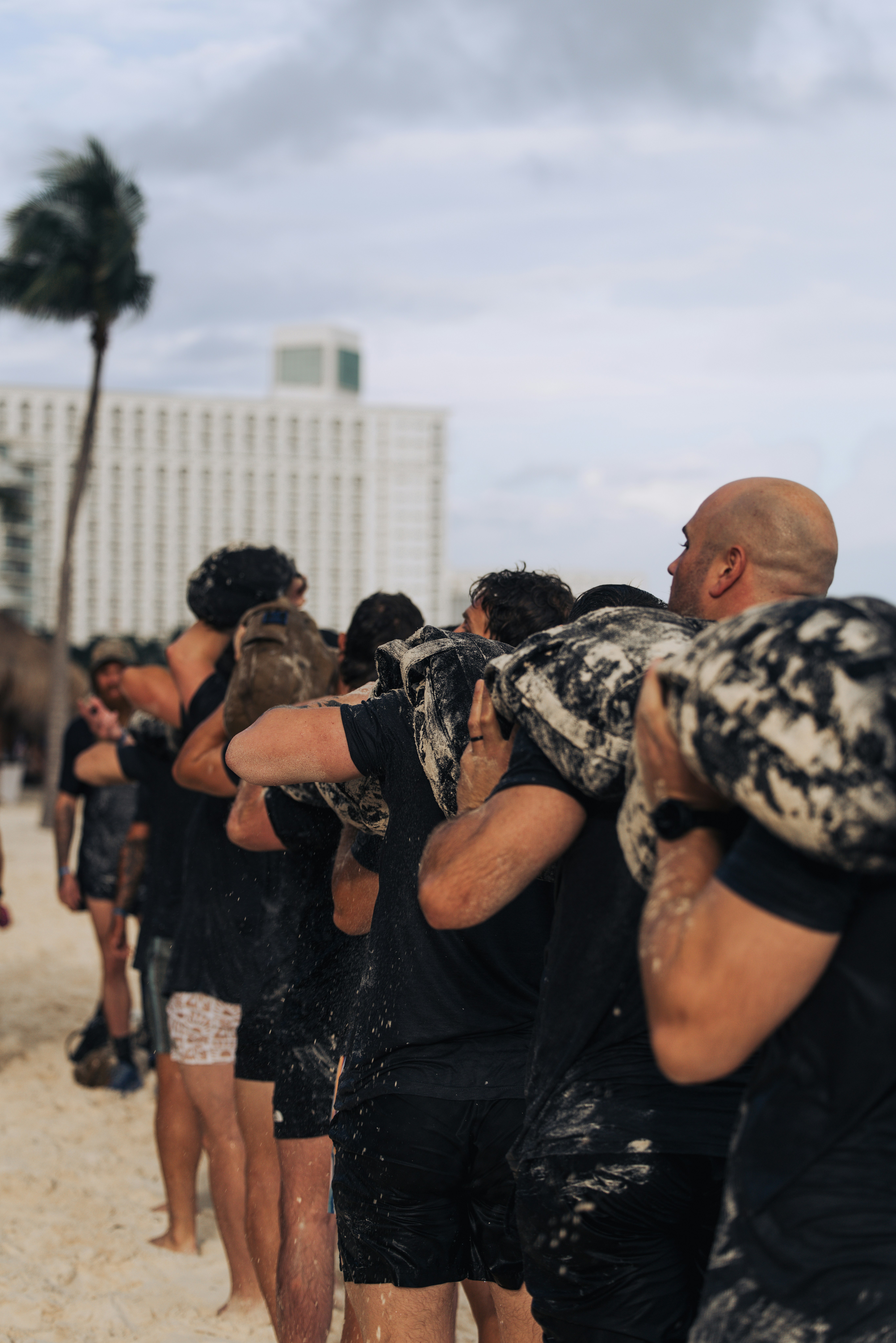 People in black shirts carrying heavy objects on beach