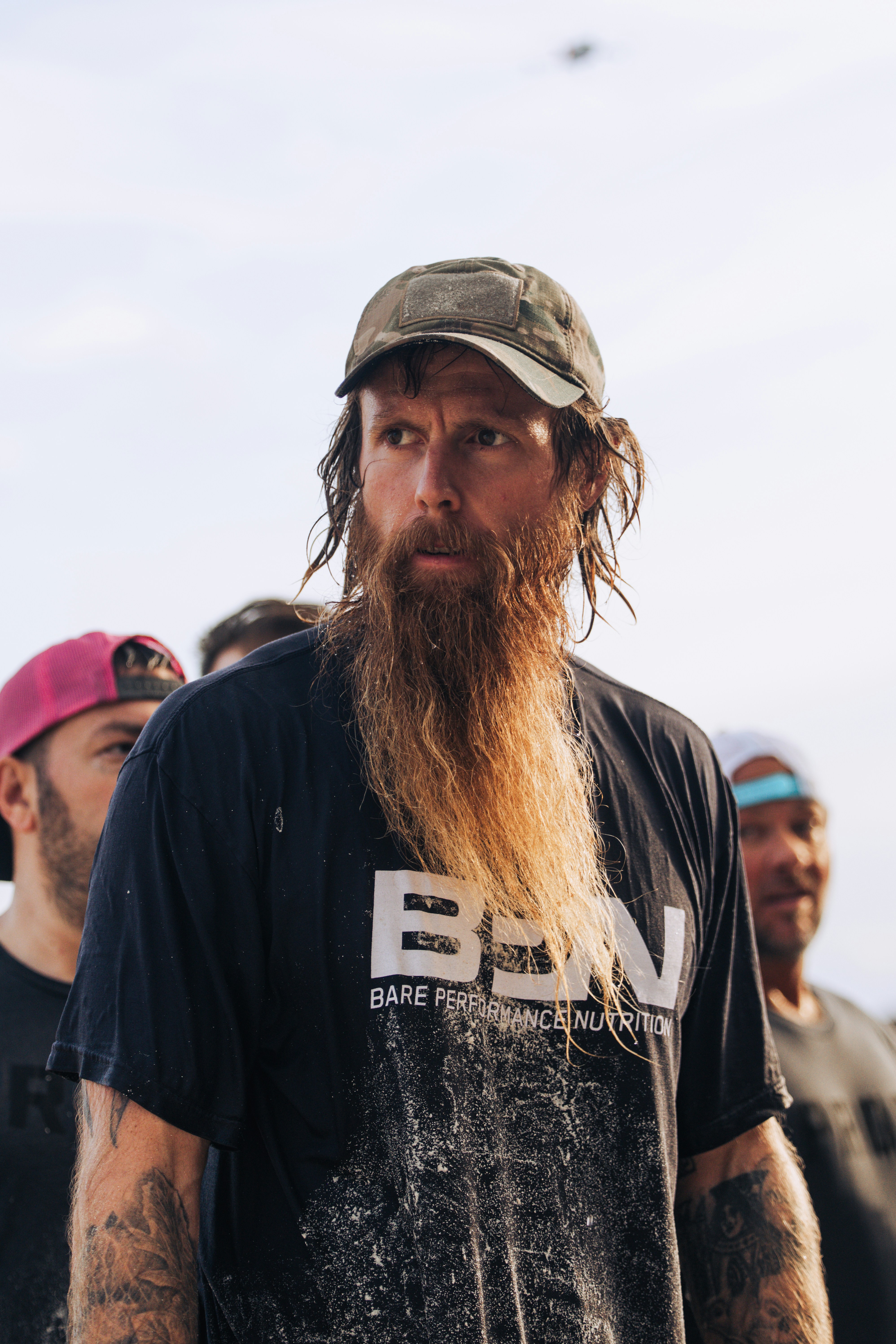 Man with long beard wearing a baseball cap and t-shirt