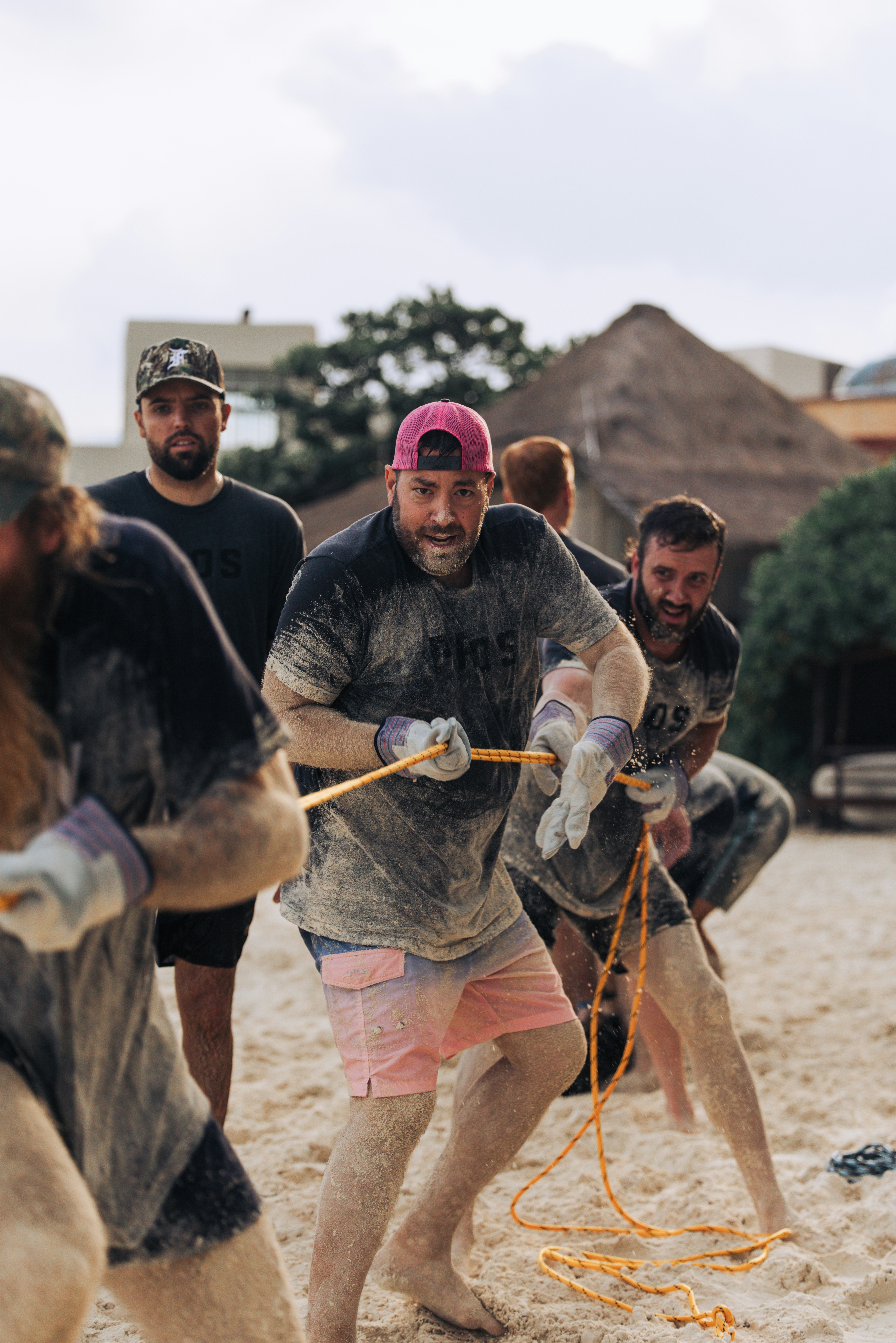 Men playing tug-of-war on a sandy beach.