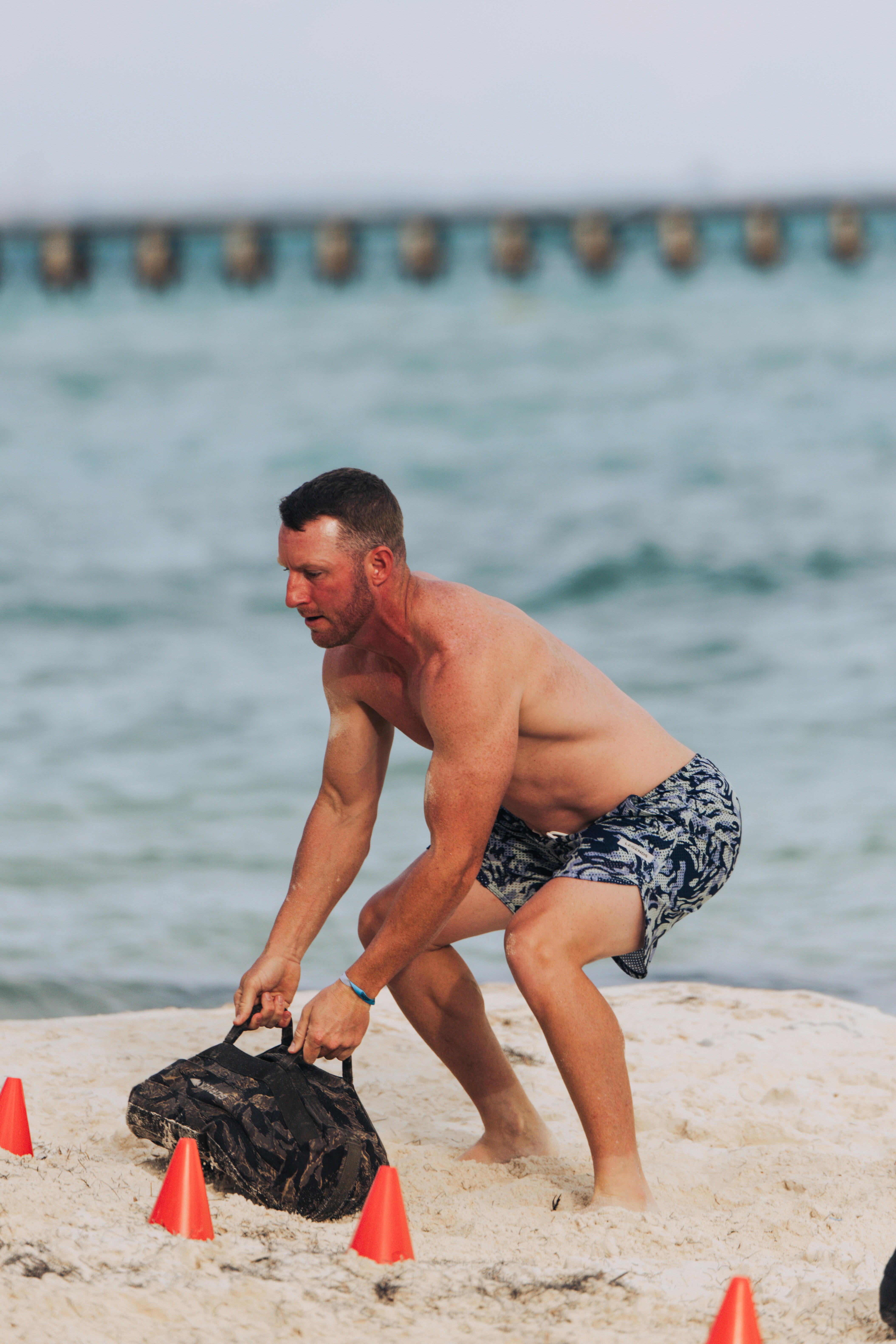 Man exercising with sandbag on beach