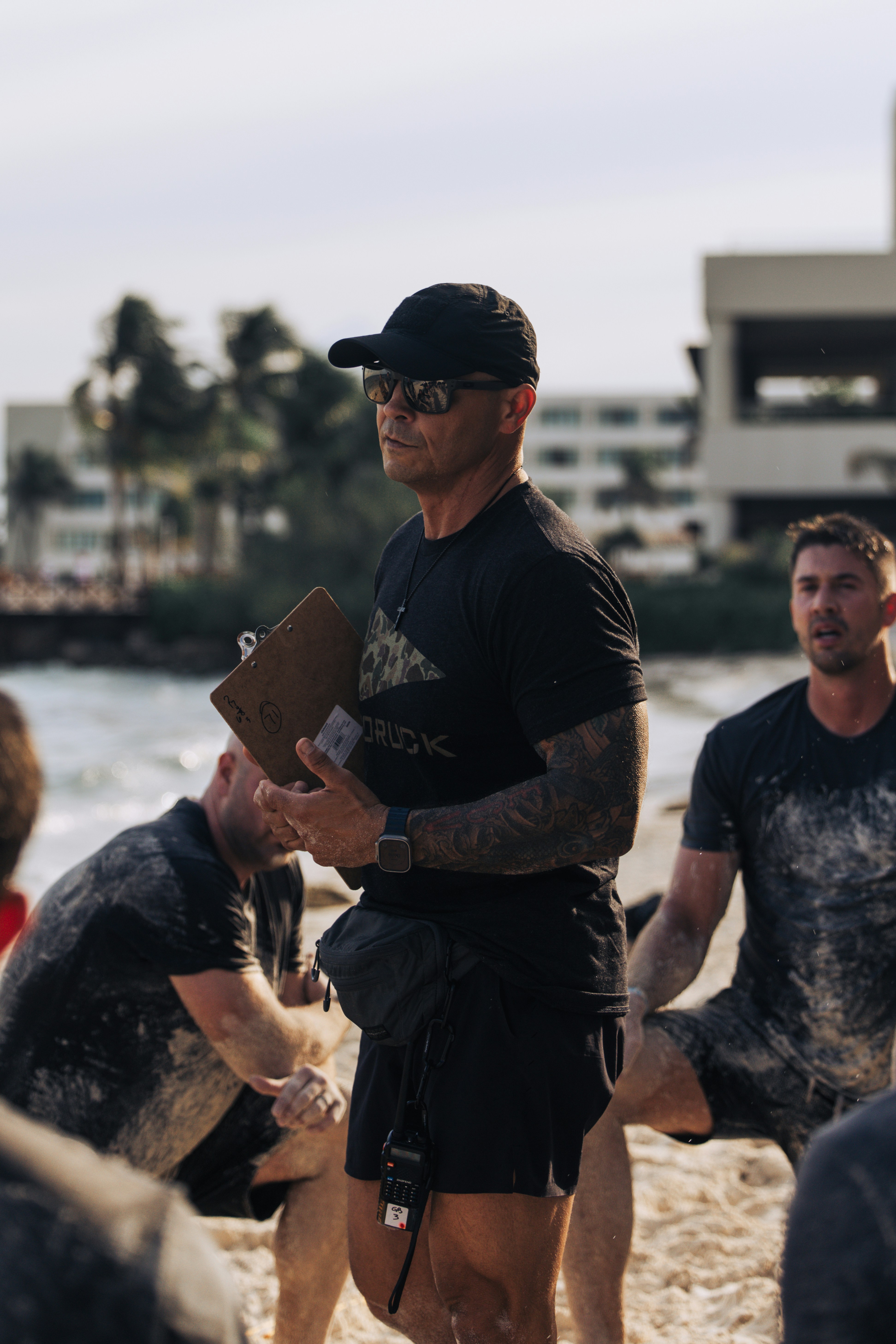 Man in cap and sunglasses holding clipboard on beach