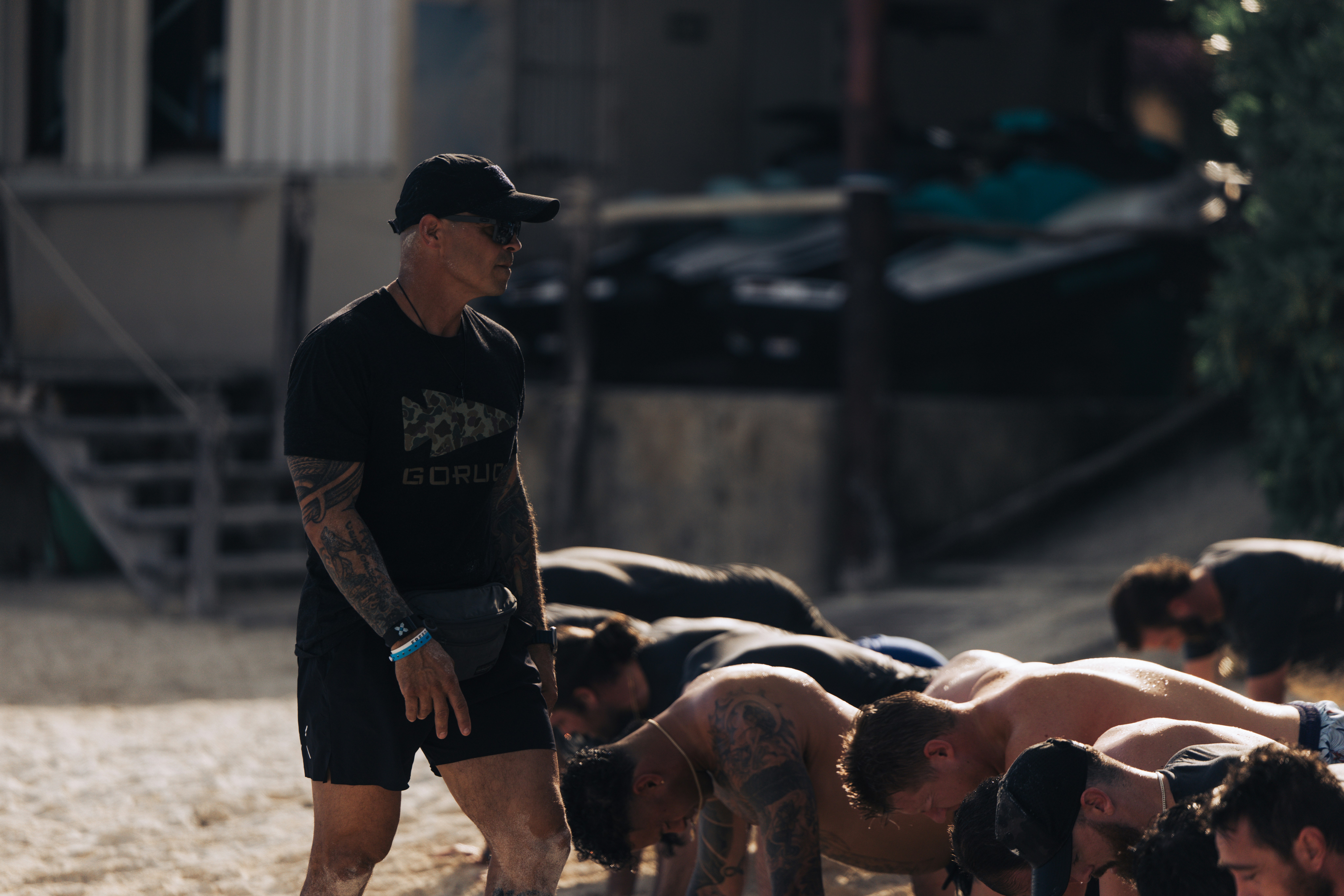 Trainer watches athletes doing push-ups outdoors