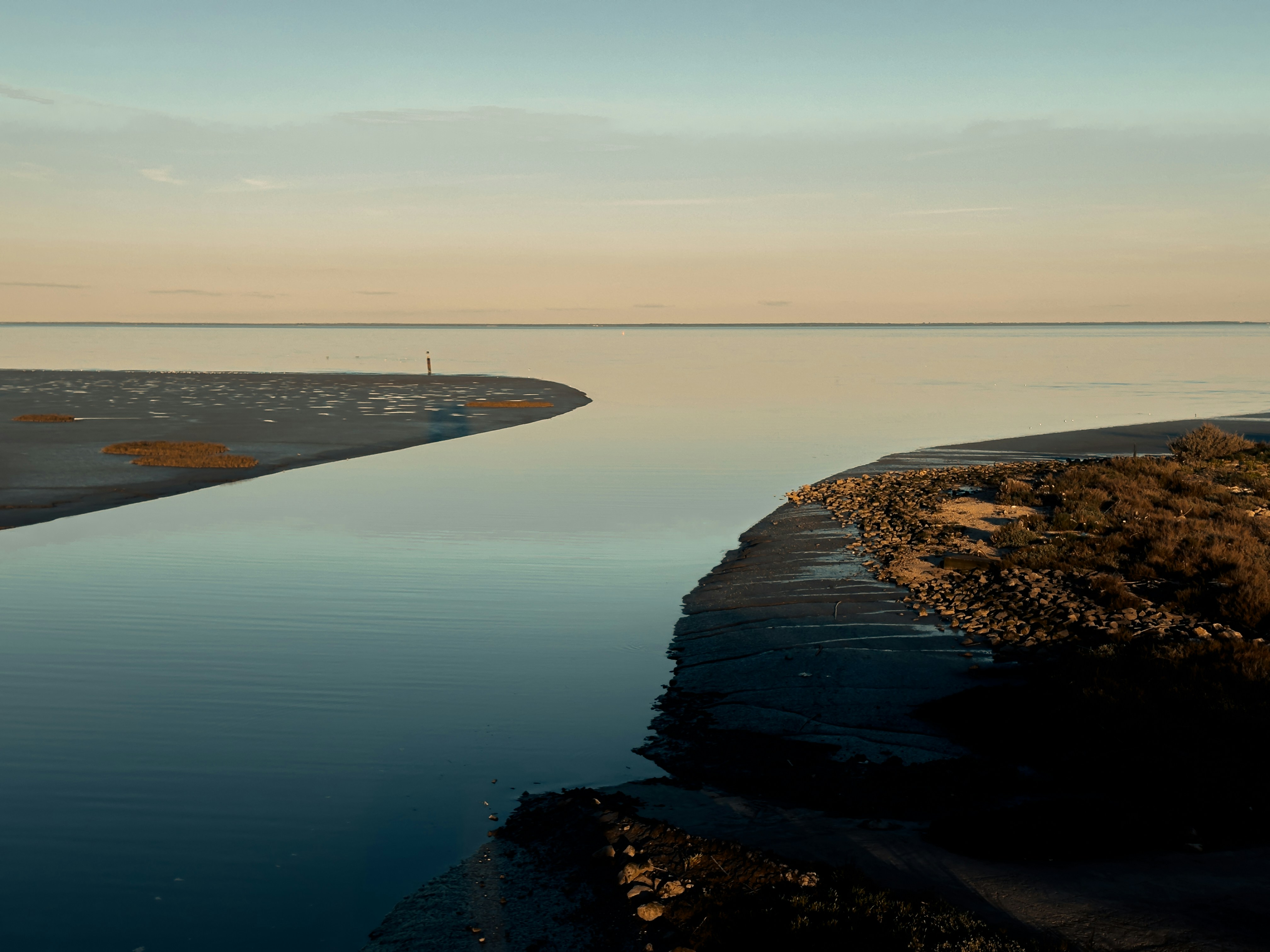Calm ocean meets a sandy shore at dusk