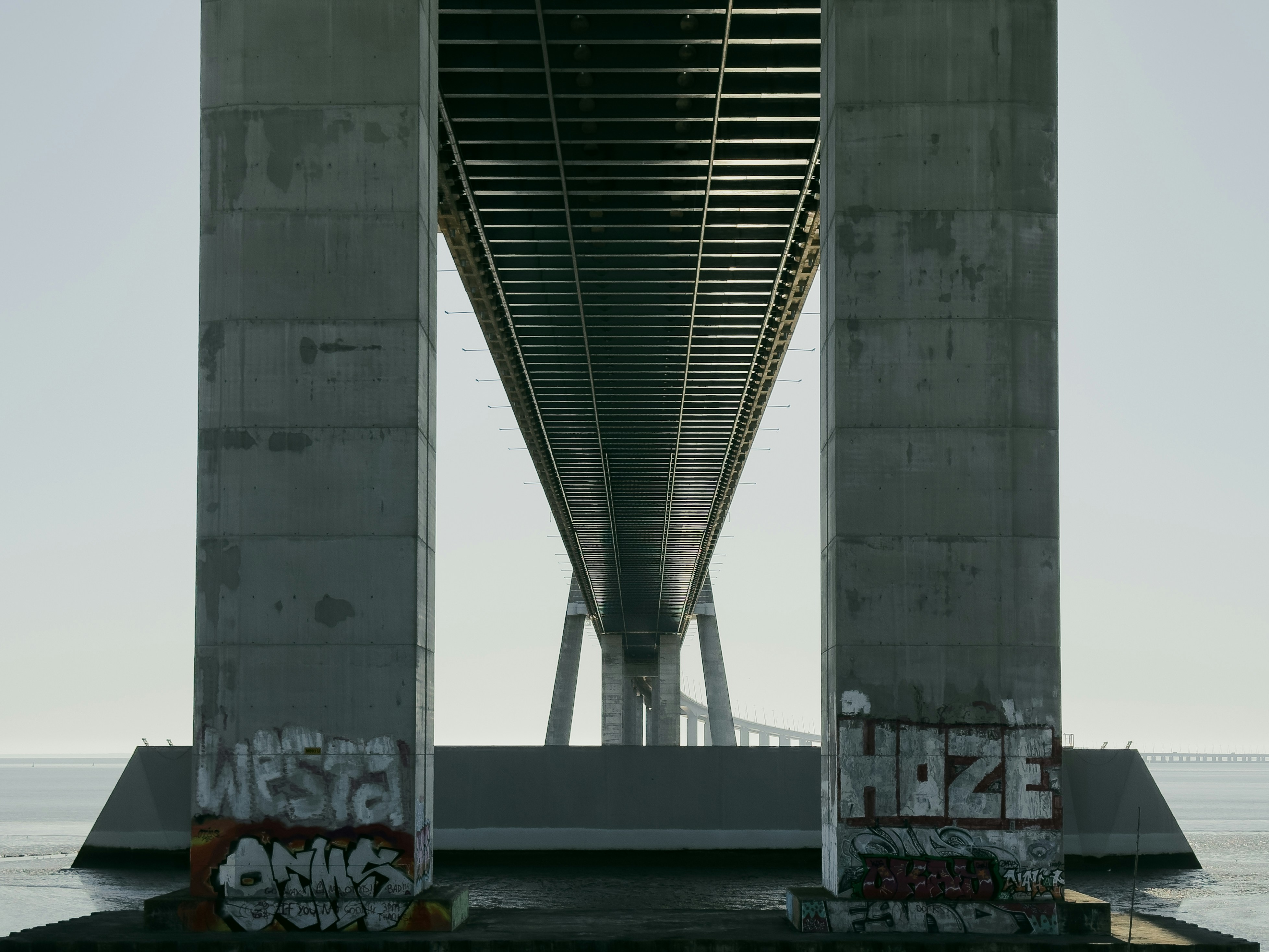Underside of a bridge with graffiti on pillars.