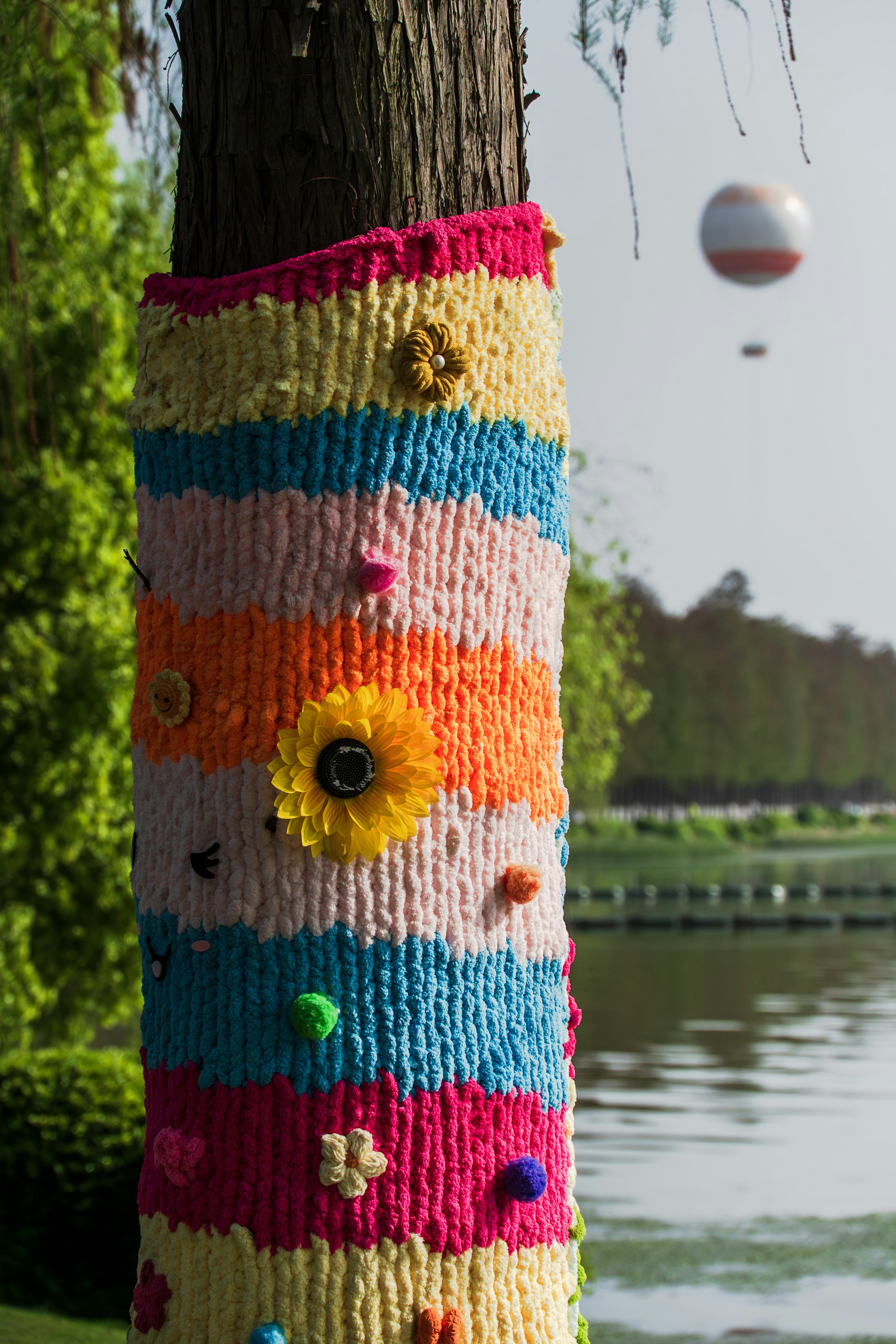 Tronco d'albero decorato con filati colorati lavorati a maglia e decorazioni