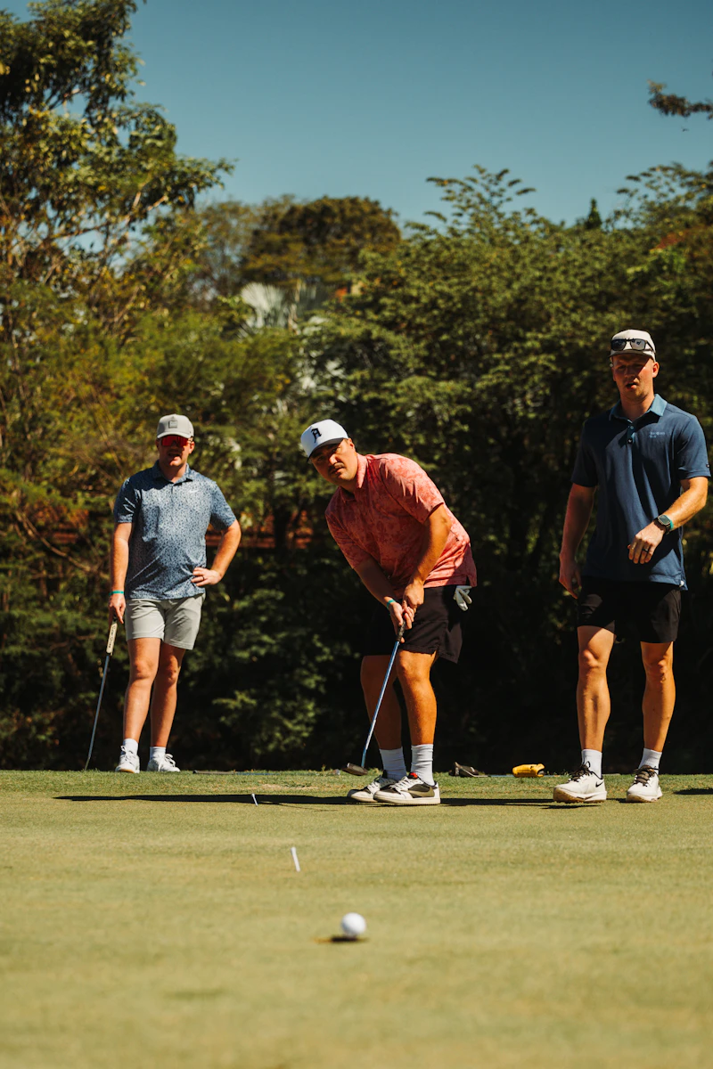 Three golfers lining up a shot on a sunny day