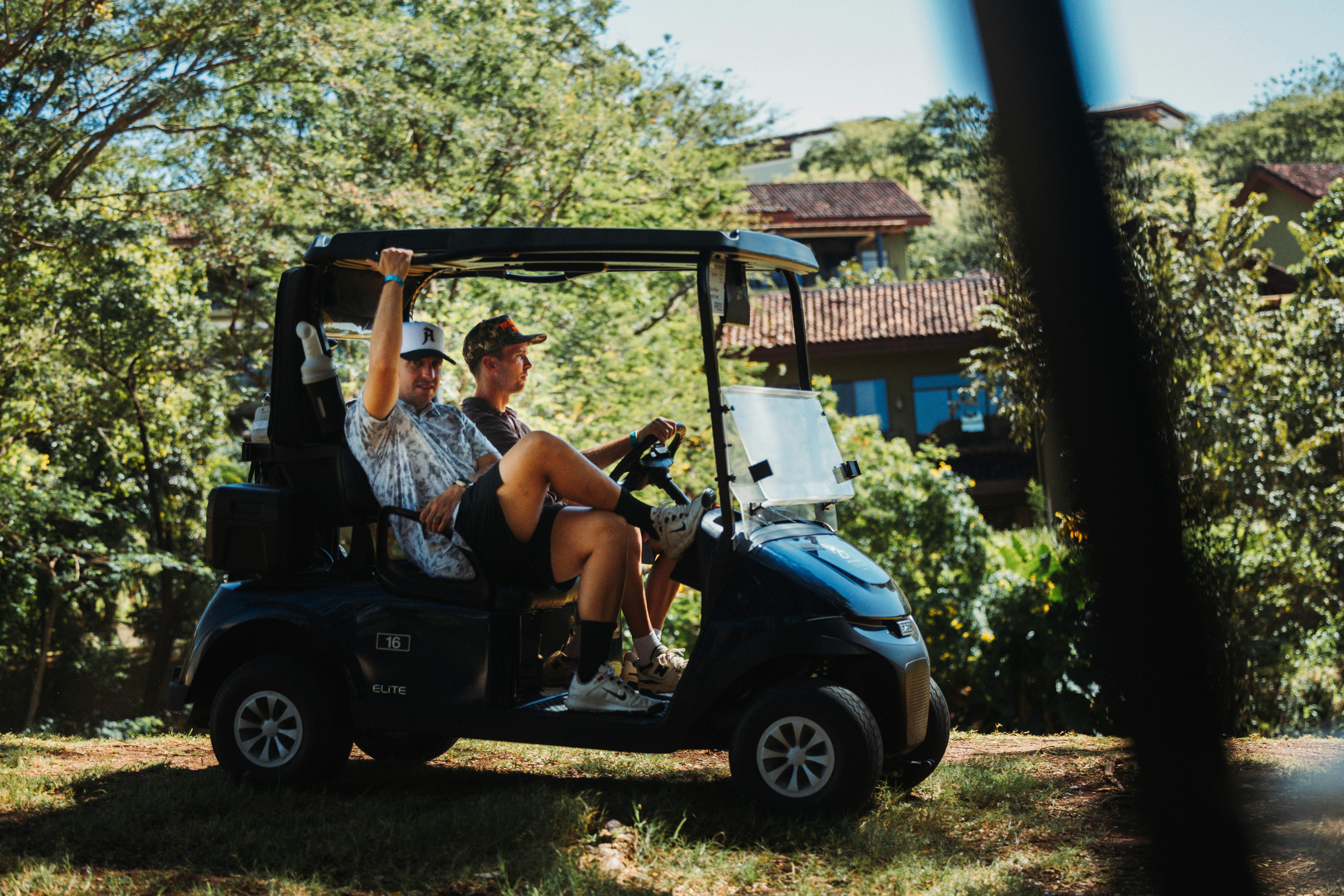 Two friends riding in a golf cart outdoors.