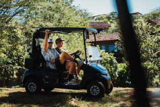 Two friends riding in a golf cart outdoors.