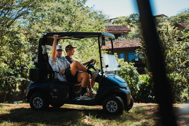 Two friends riding in a golf cart outdoors.