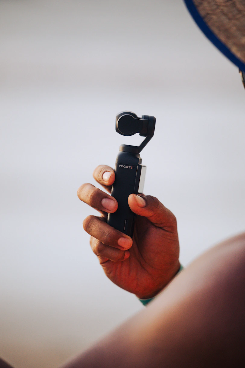Hand holding a small black gimbal camera