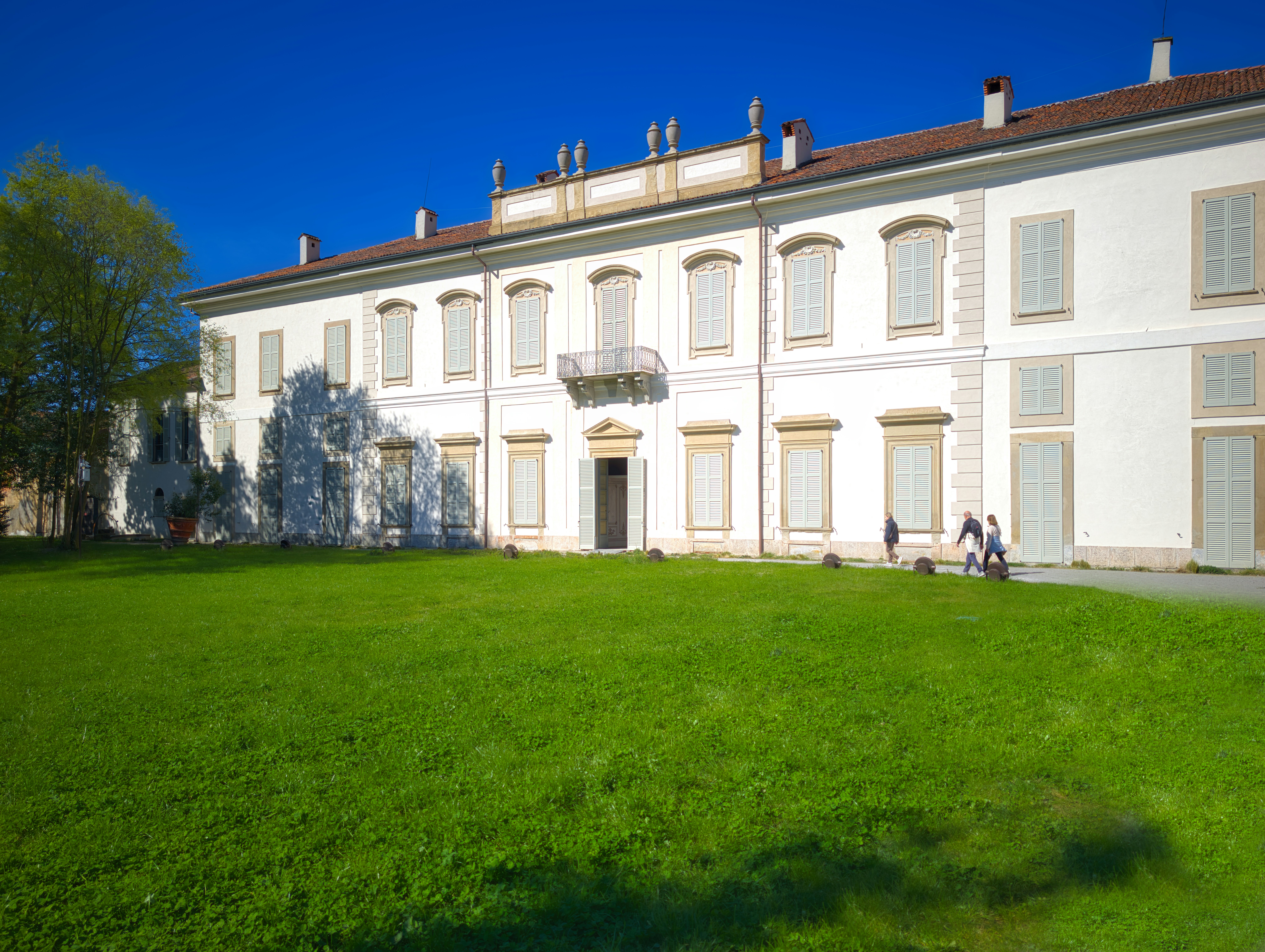 Large white building with green lawn and blue sky.