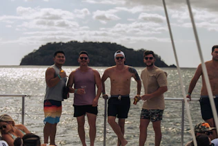 Four men standing on a boat with island in background