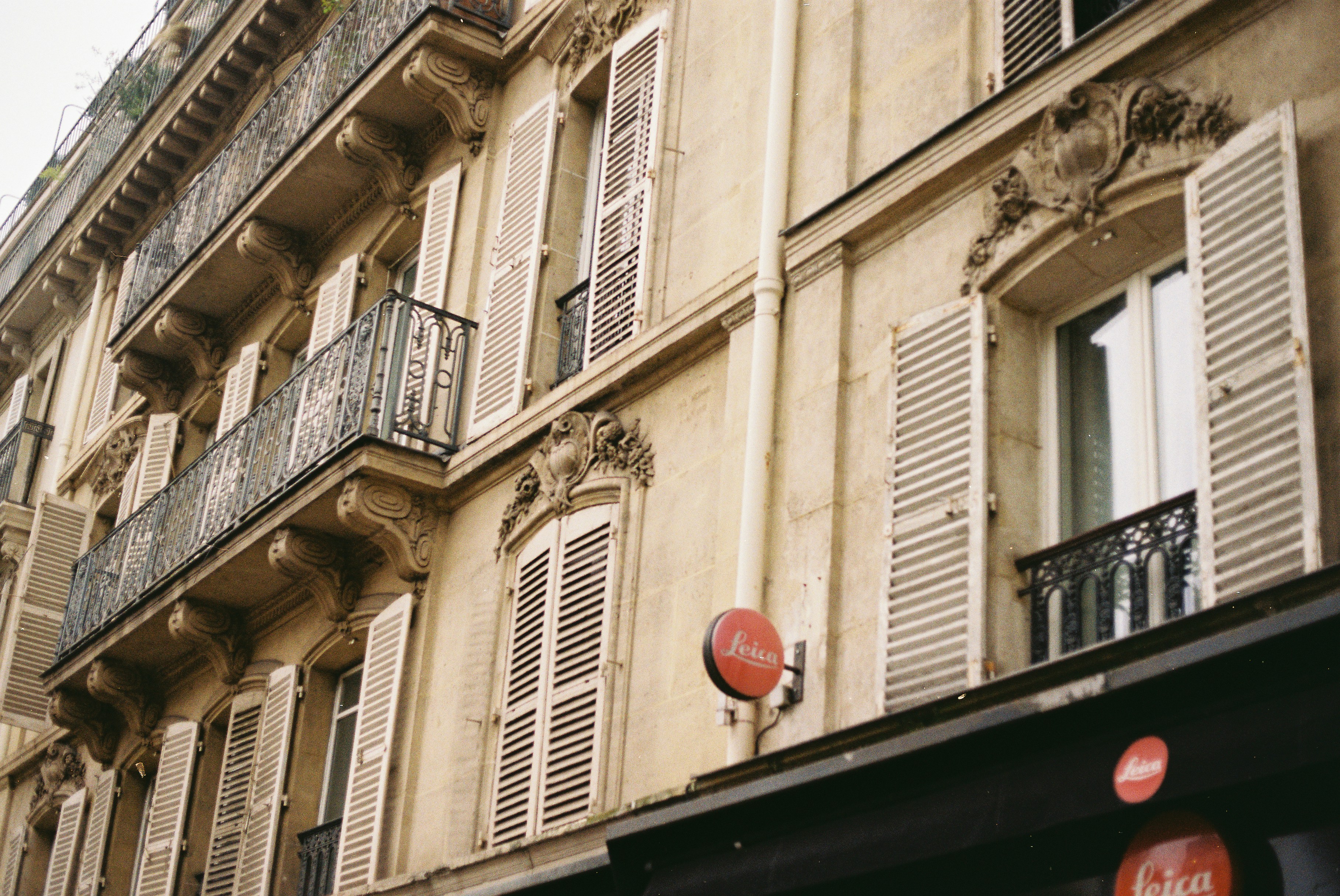 Ornate parisian building facade with shutters and balconies.