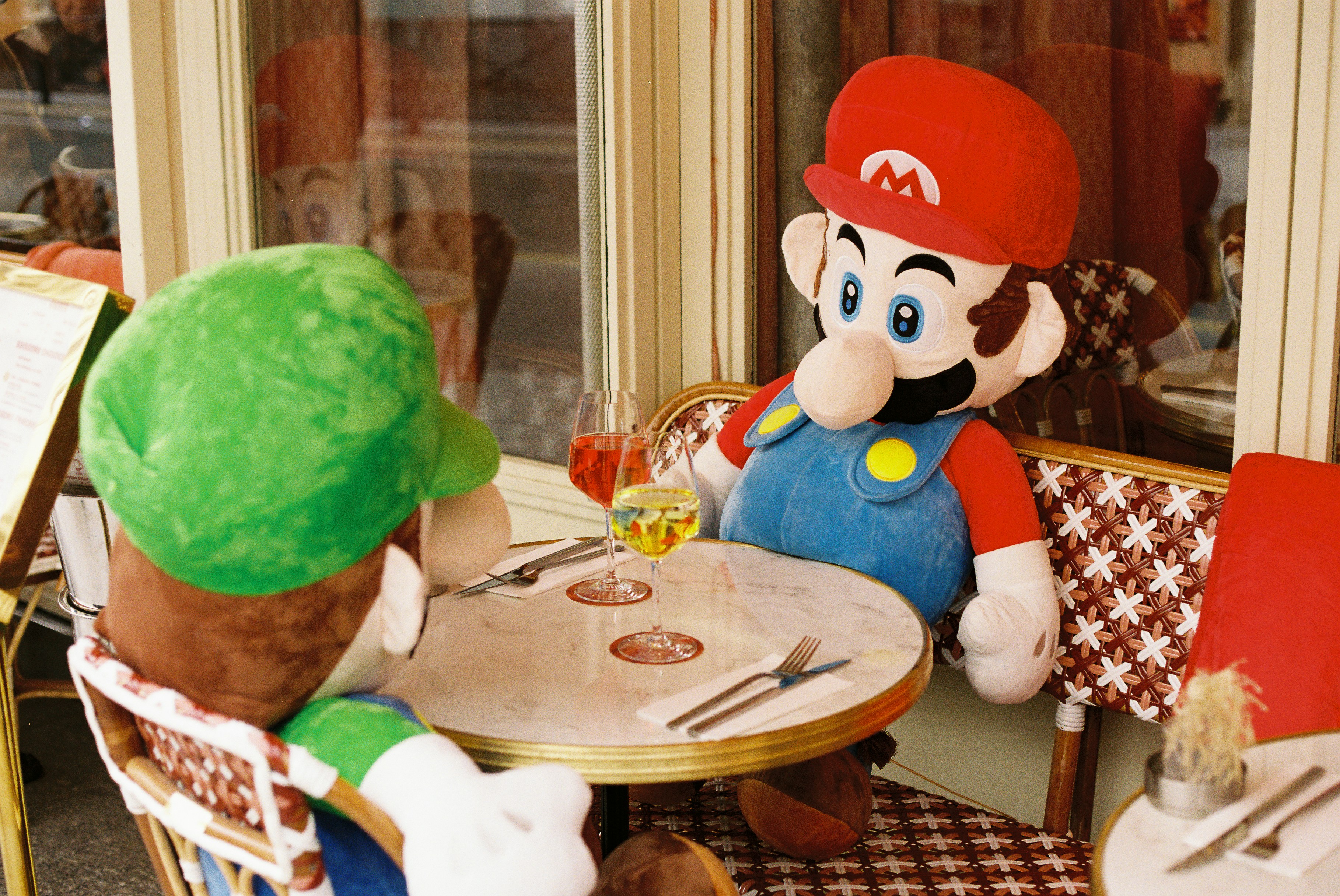 Mario und Luigi sitzen Plüschtiere an einem Cafétisch