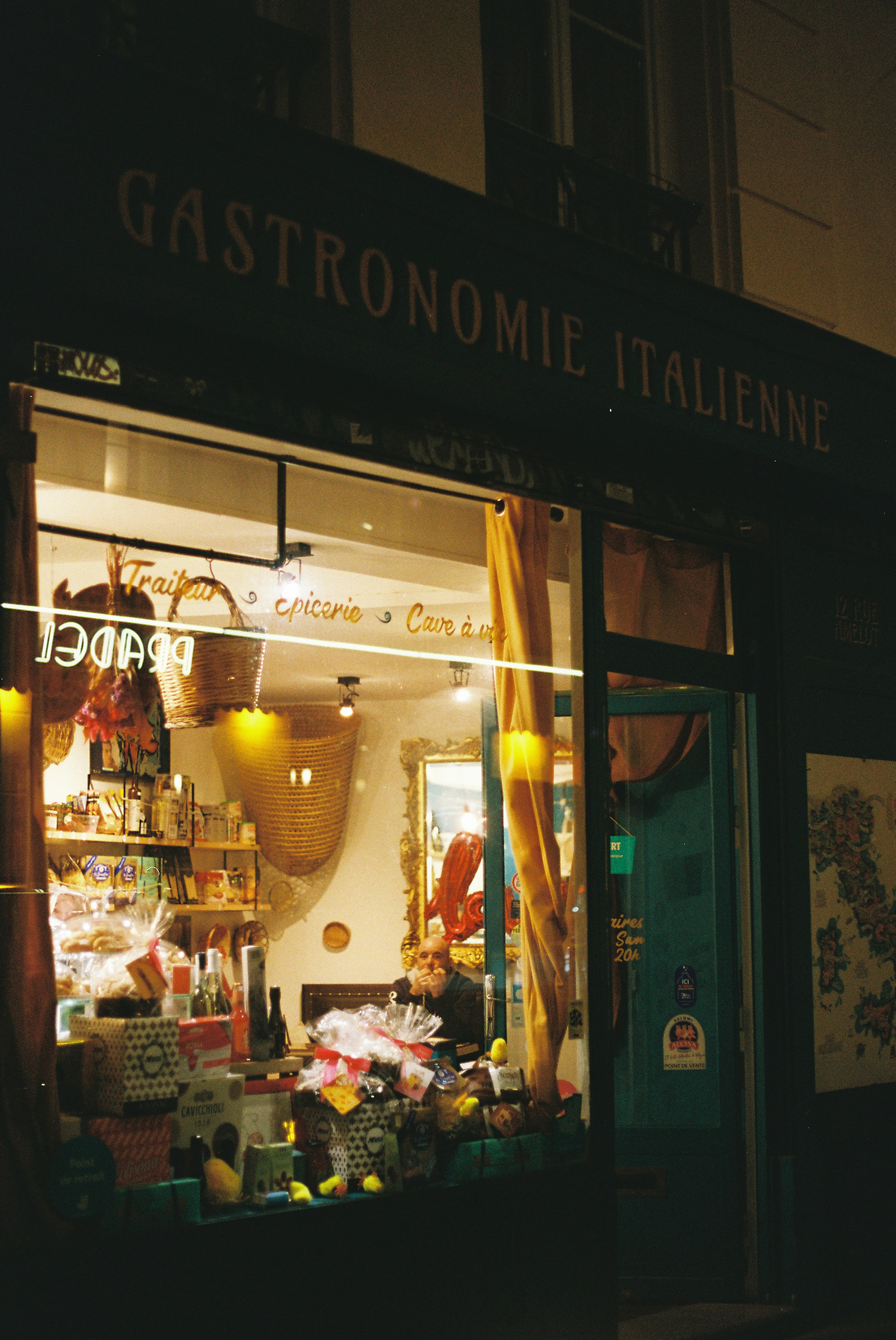 Tienda italiana de charcutería por la noche con productos expuestos.