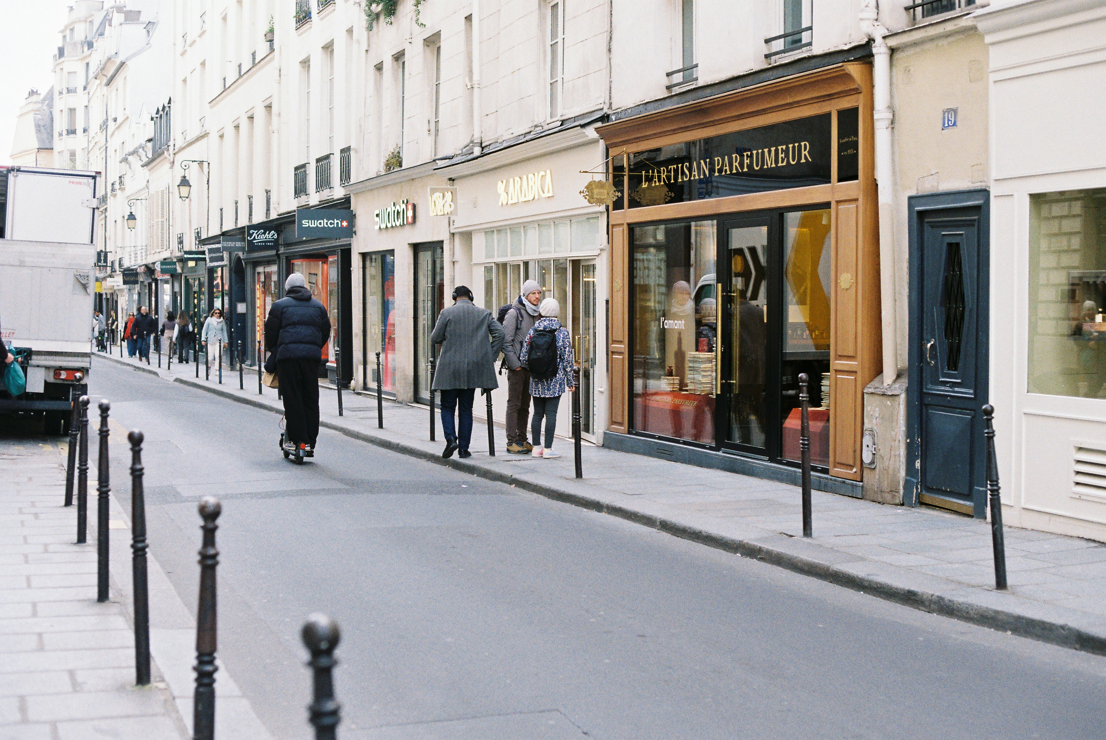 People walking down a parisian street with shops.