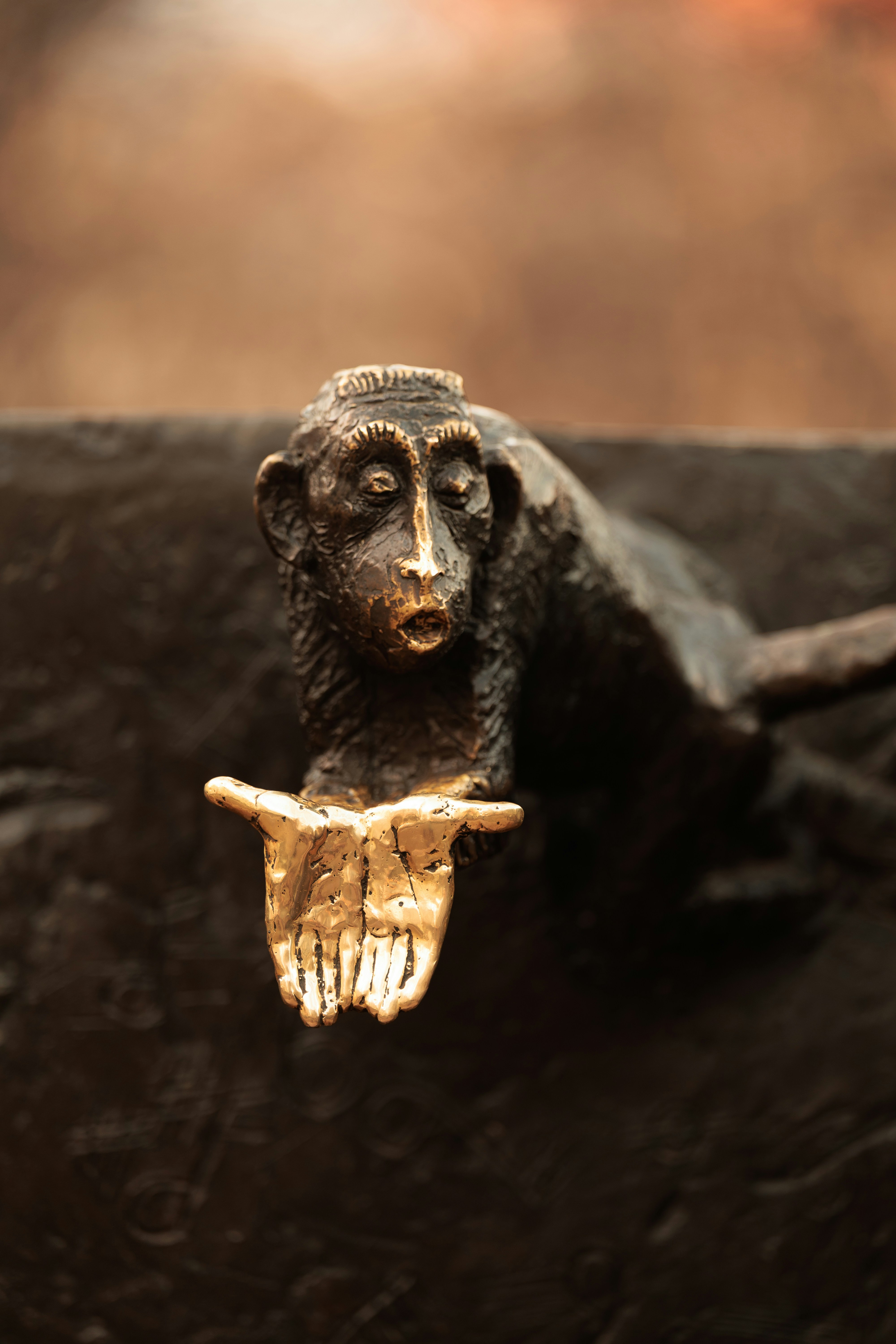 Bronzene Affenskulptur mit ausgestreckten goldenen Händen