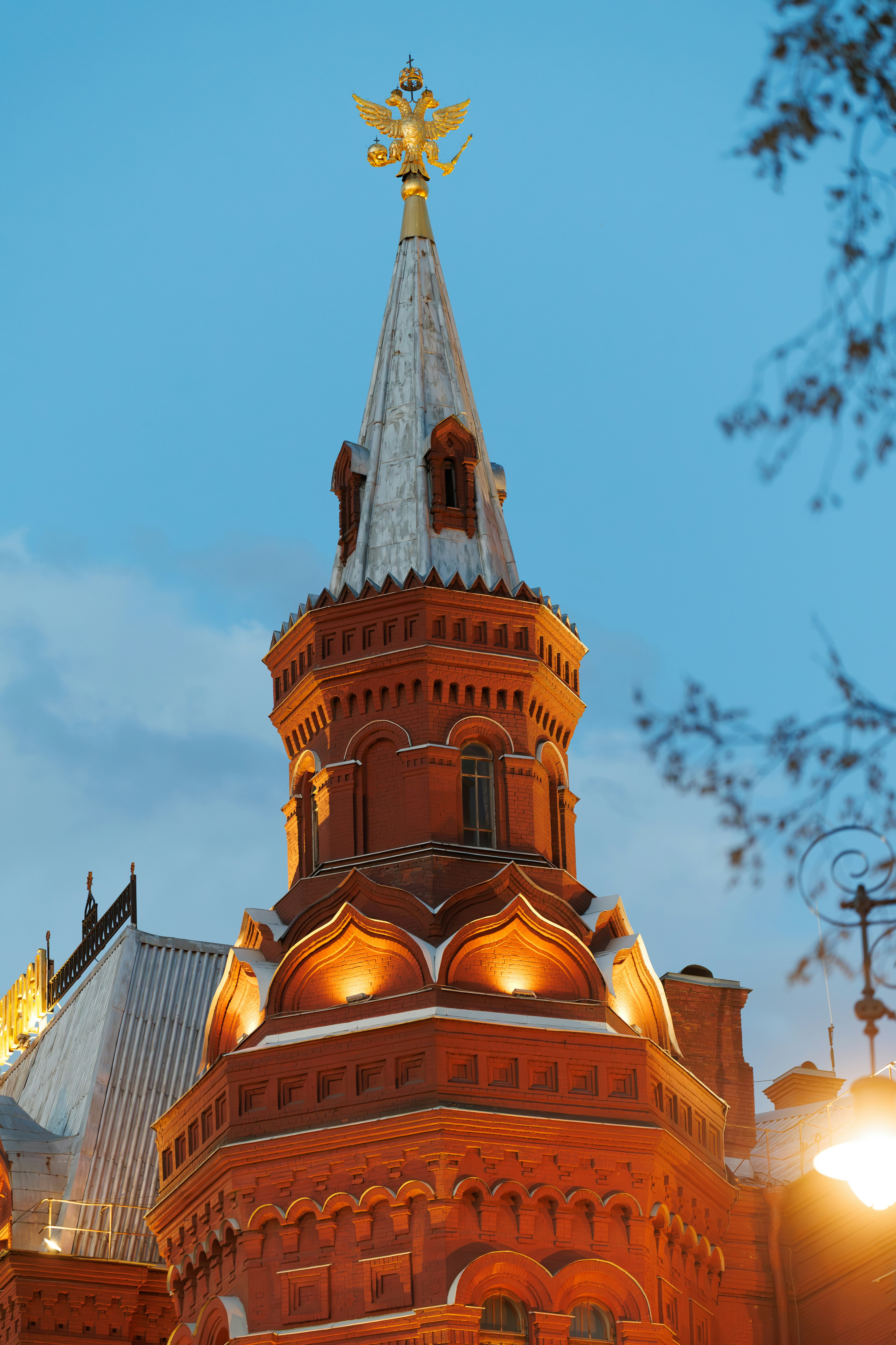 Verzierter roter Backsteinturm mit dem Goldadler bei Einbruch der Dämmerung.