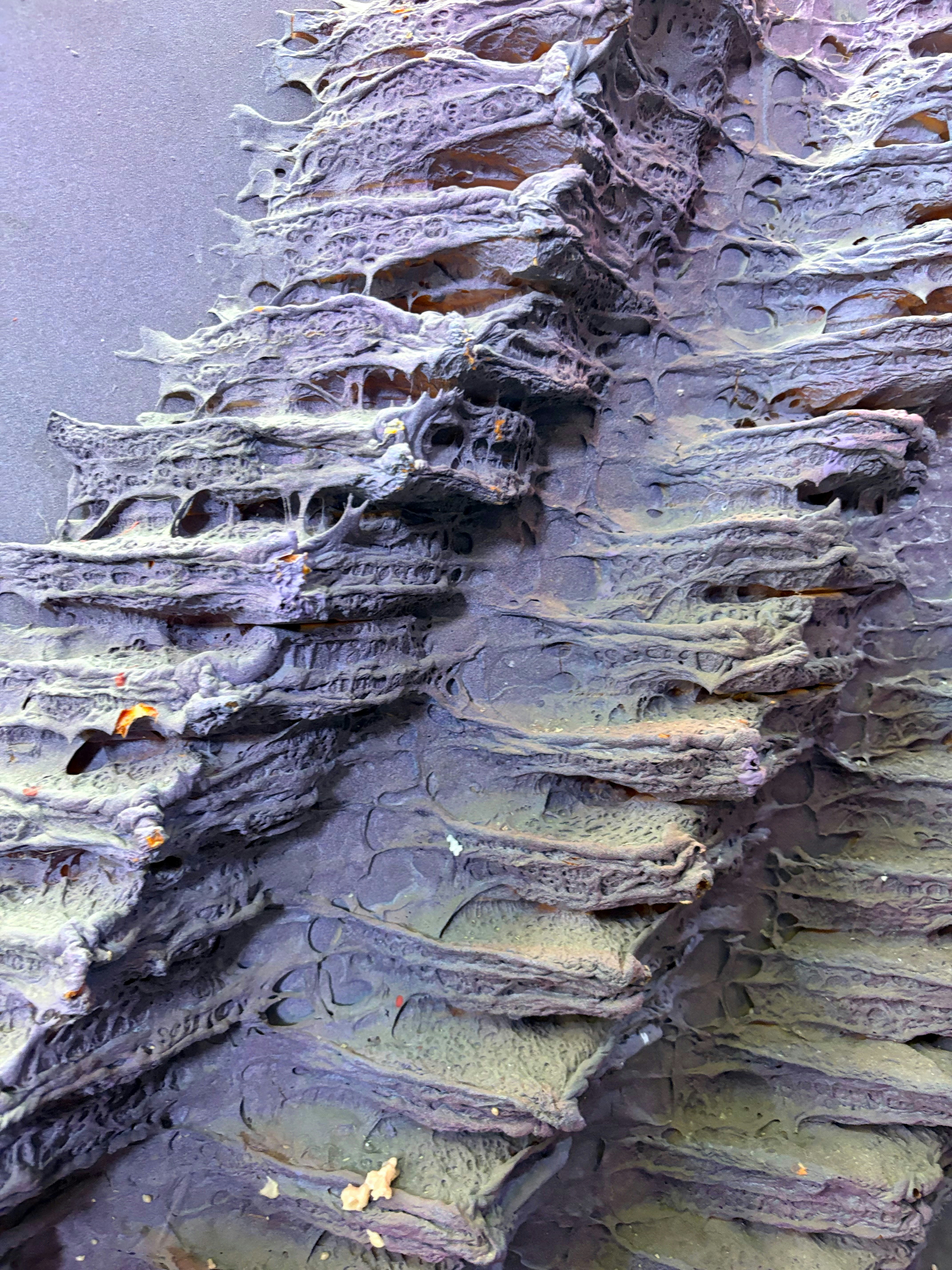 초록색과 보라색 빛이 섞인 층층이 쌓인 암석 지형의 클로즈업