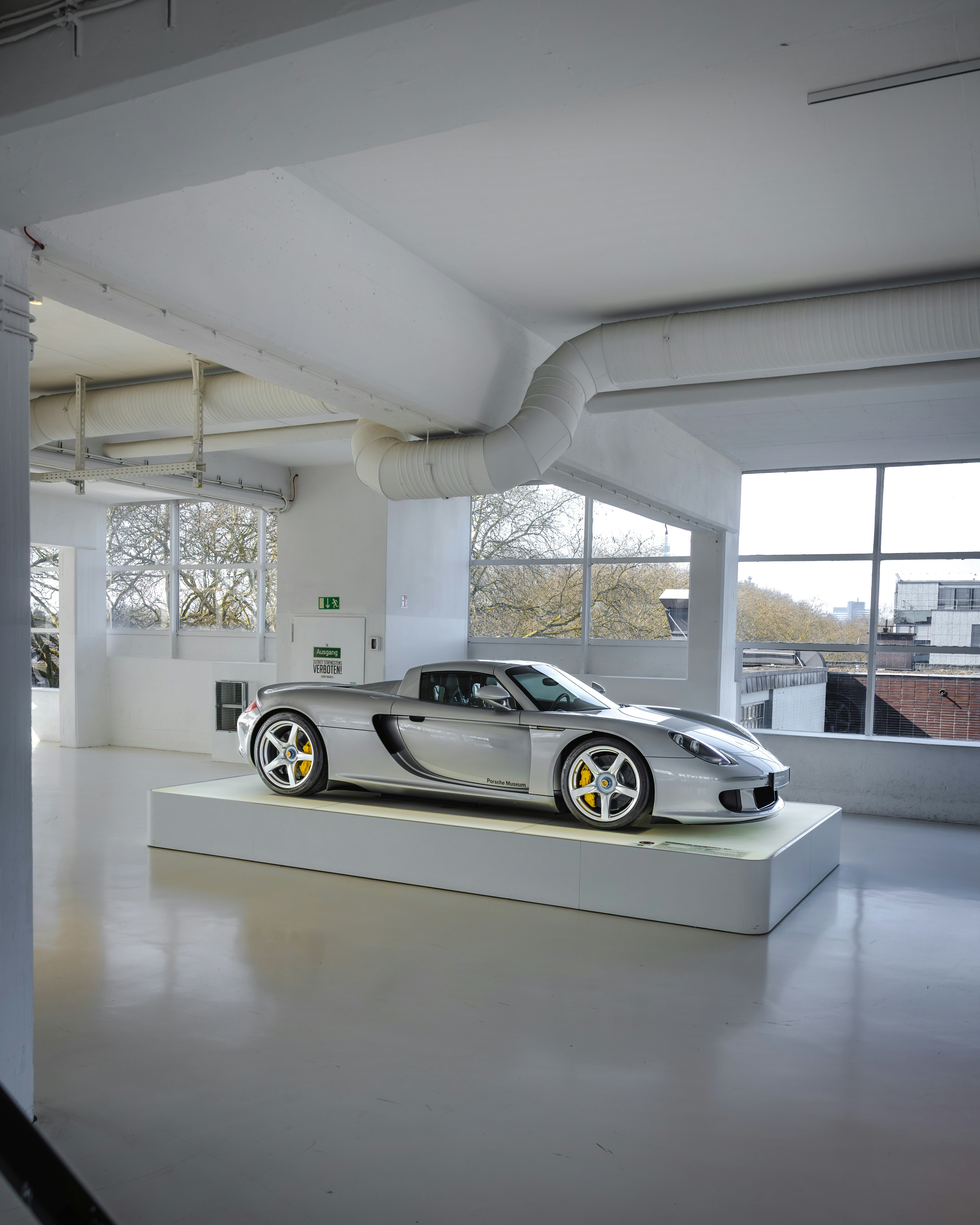 Silver porsche carrera gt on display in a bright studio.