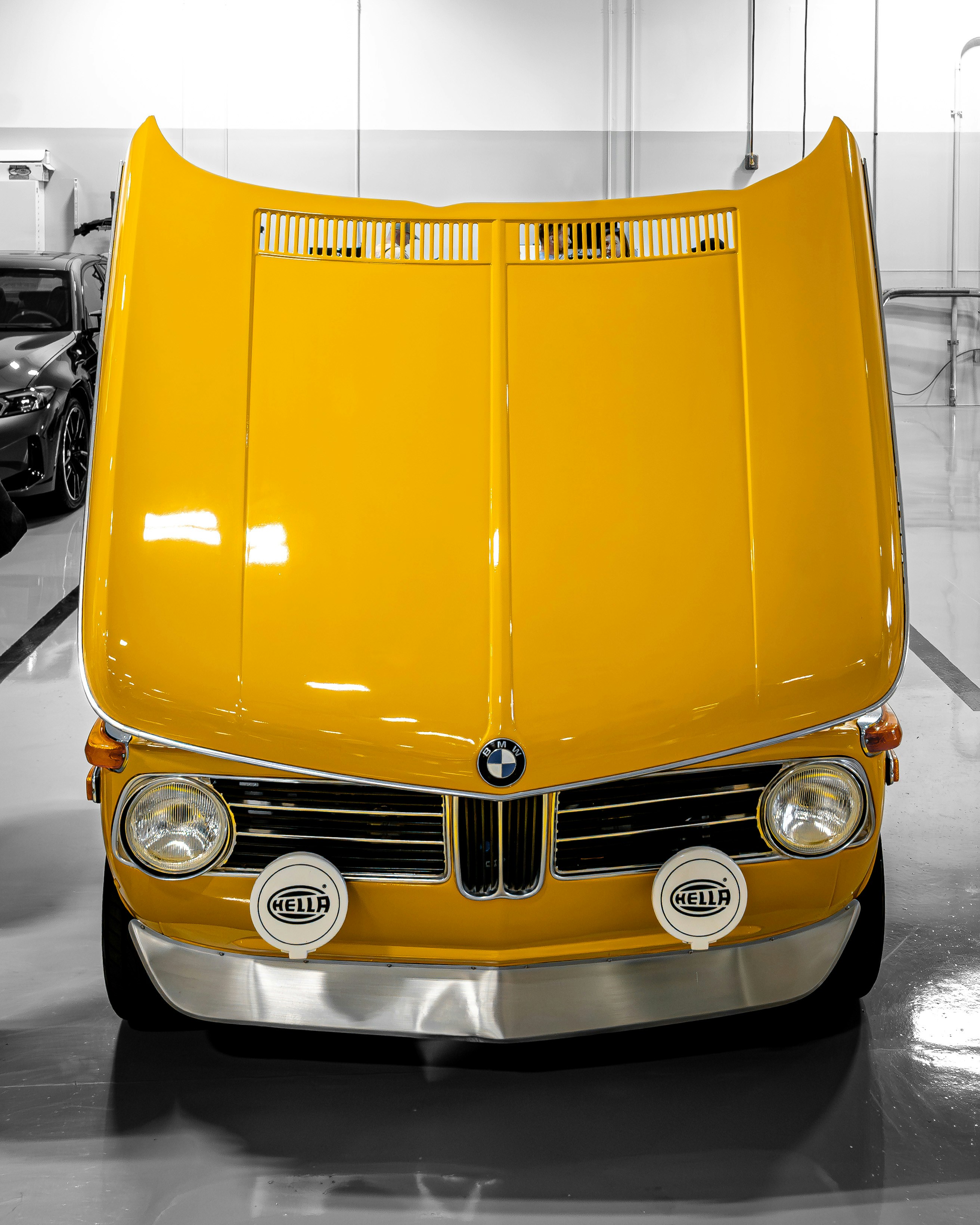 Gelber Oldtimer-BMW mit offener Motorhaube