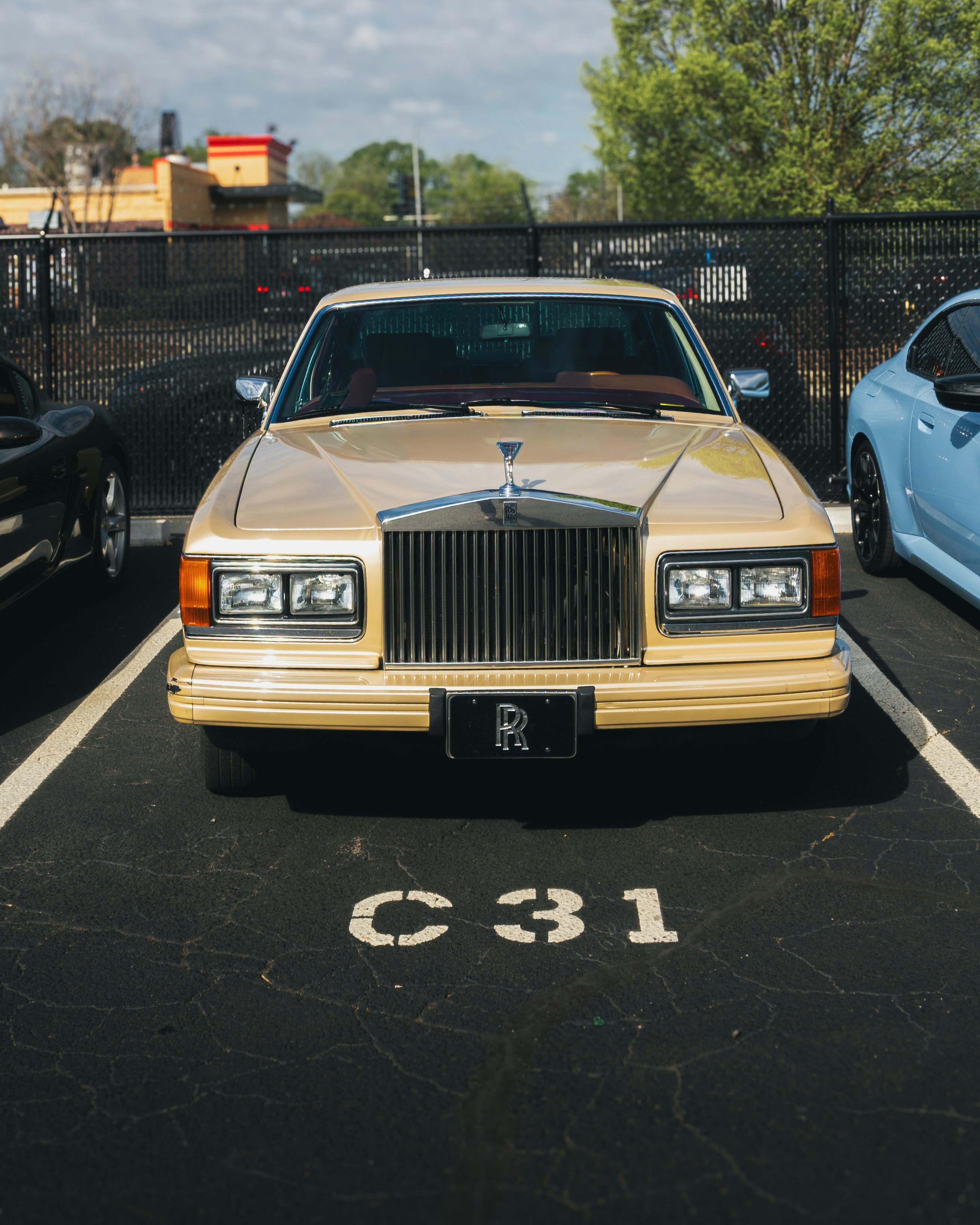 Ein goldener Rolls-Royce steht auf einem Parkplatz.