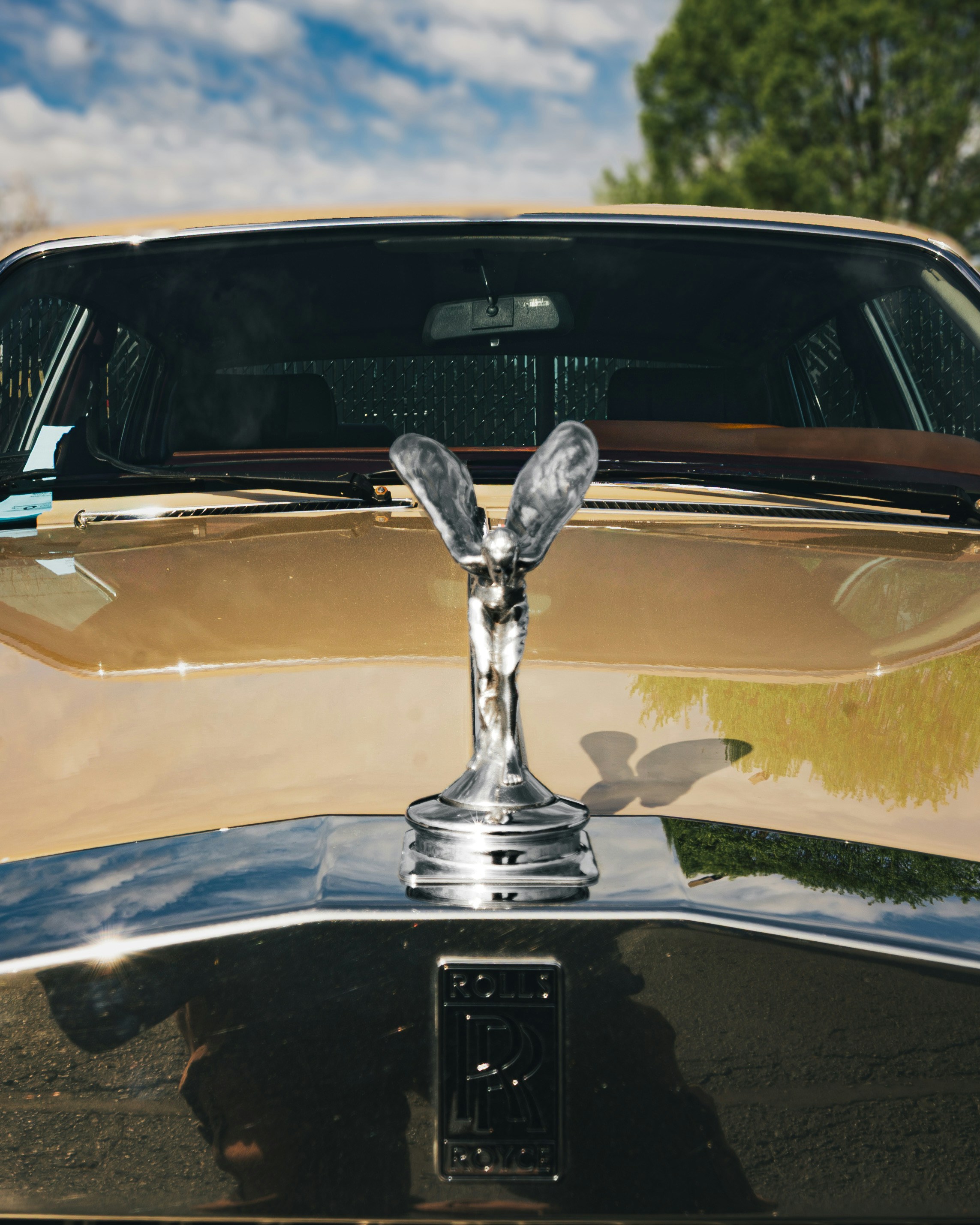 Goldene Rolls-Royce-Motorhaubenornament mit blauem Himmel.