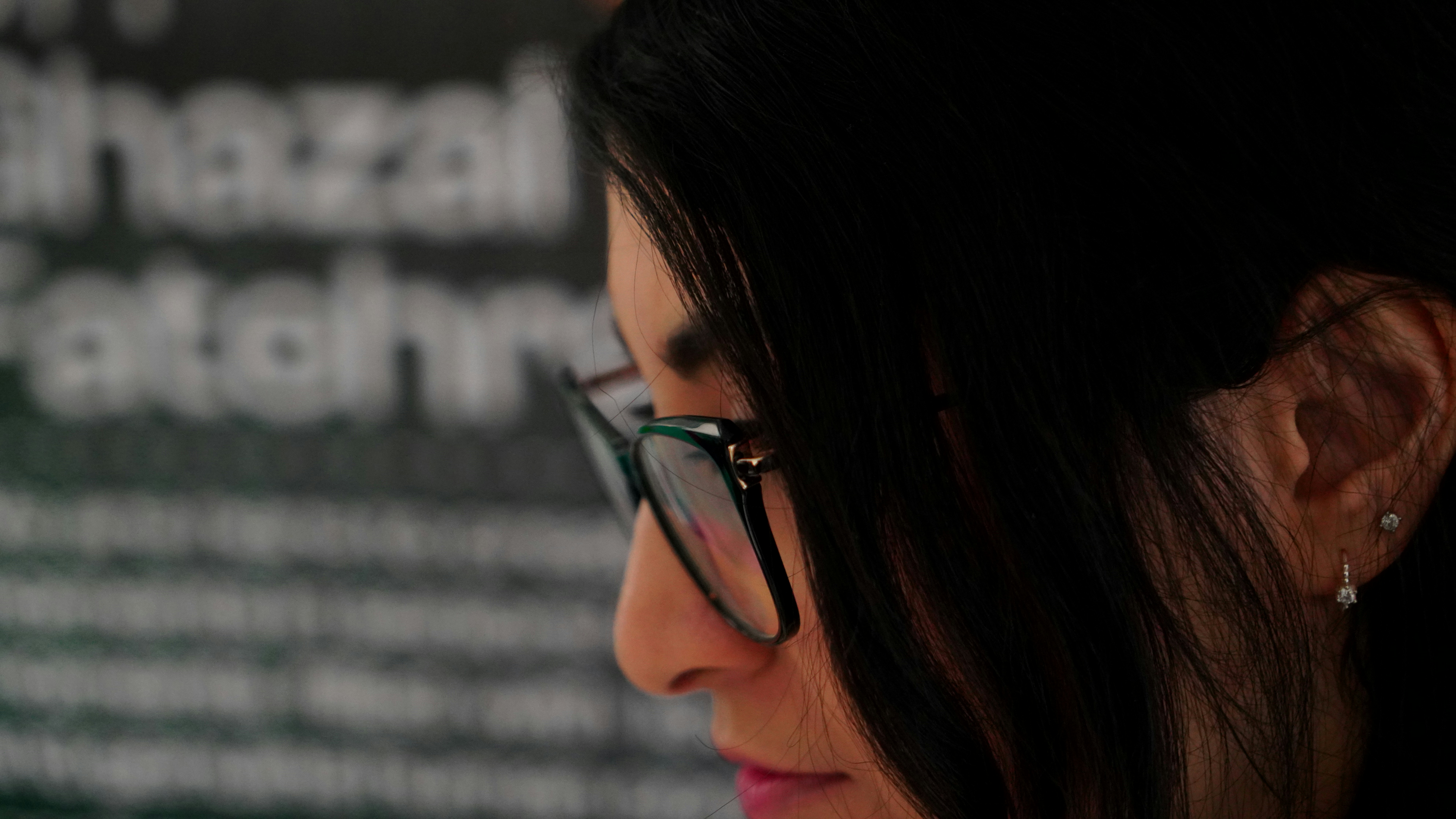 Woman wearing glasses looking at text on wall