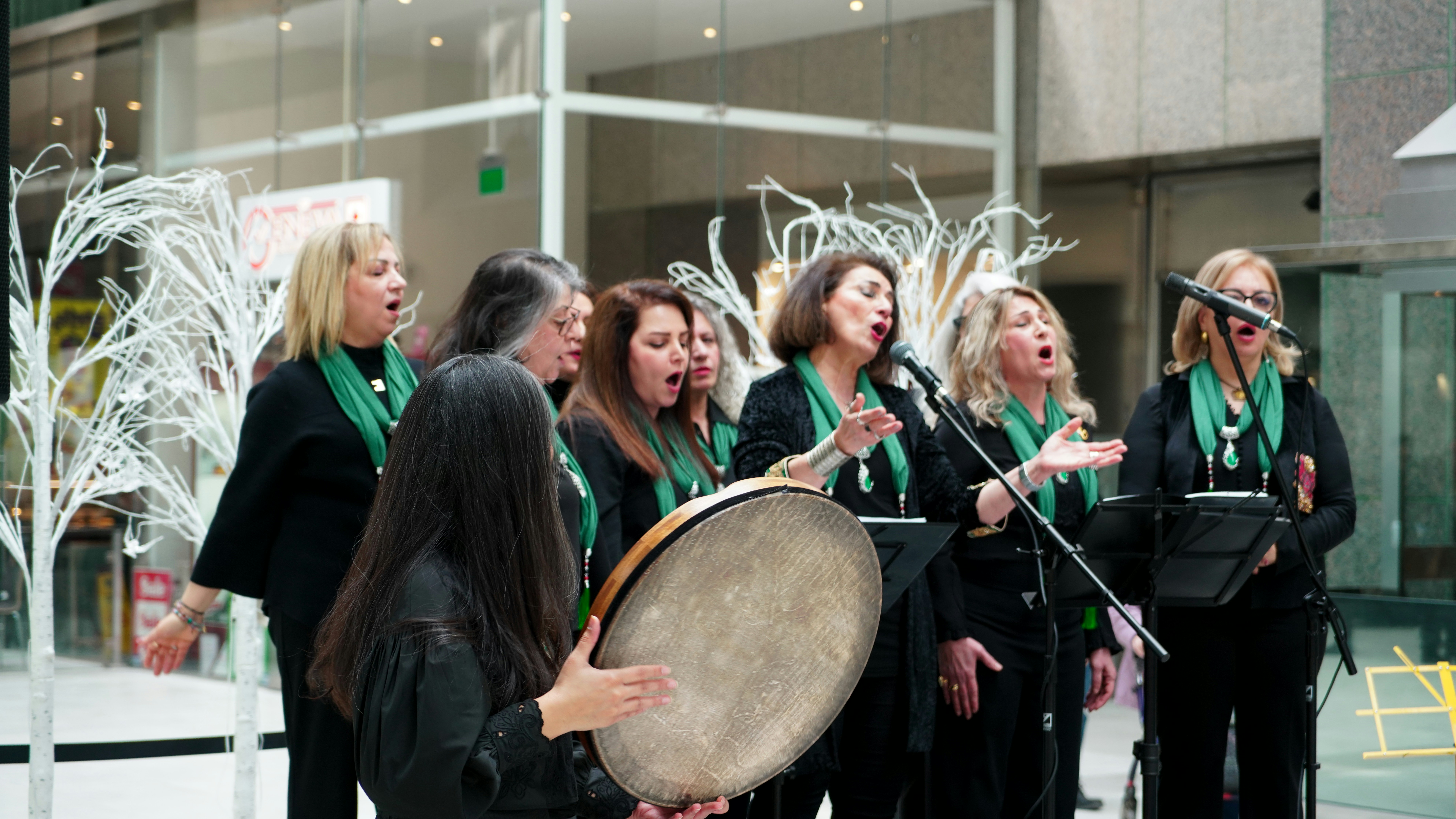 A group of women singing and playing a drum