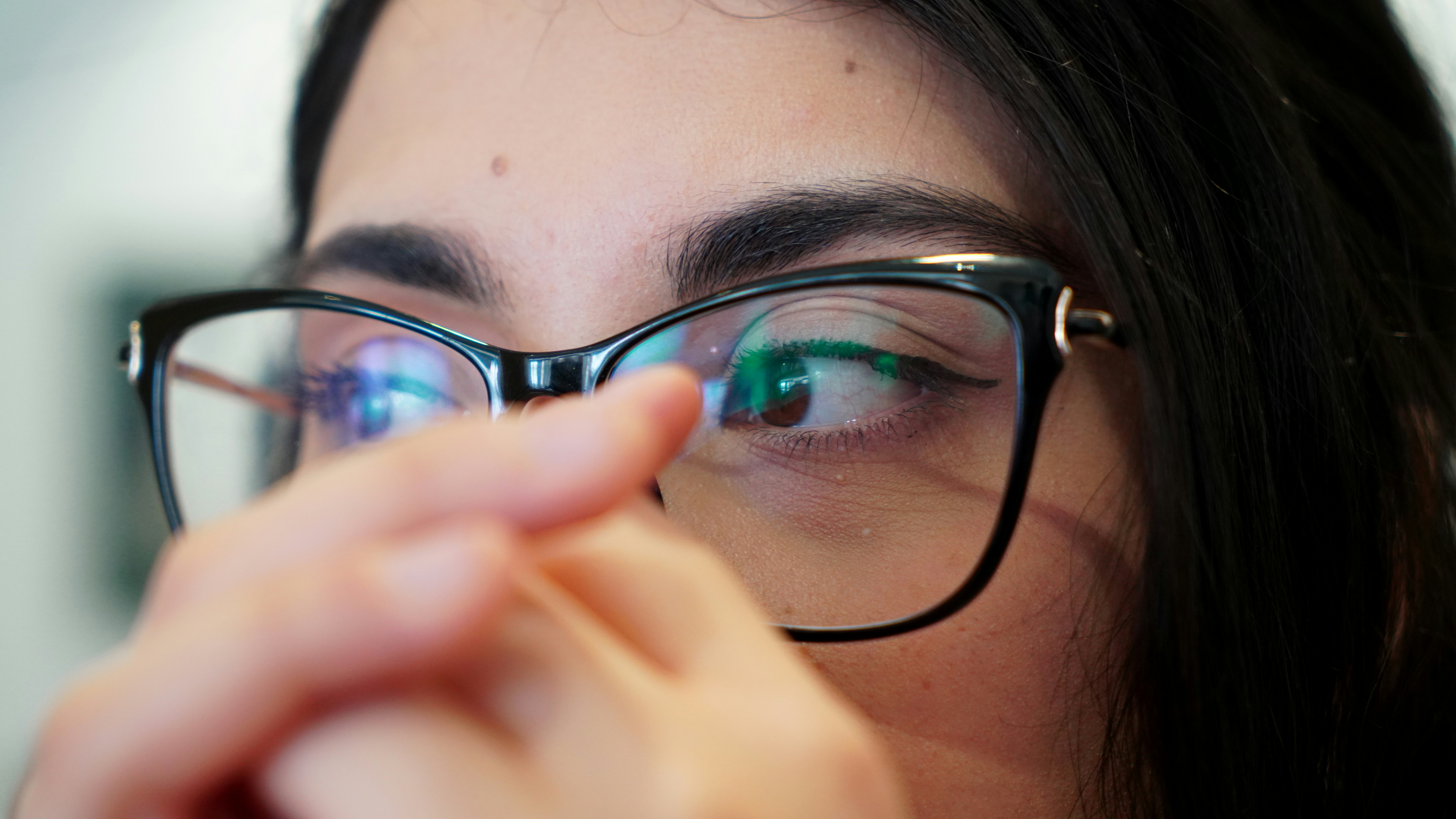 A woman wearing glasses looks intently at something.