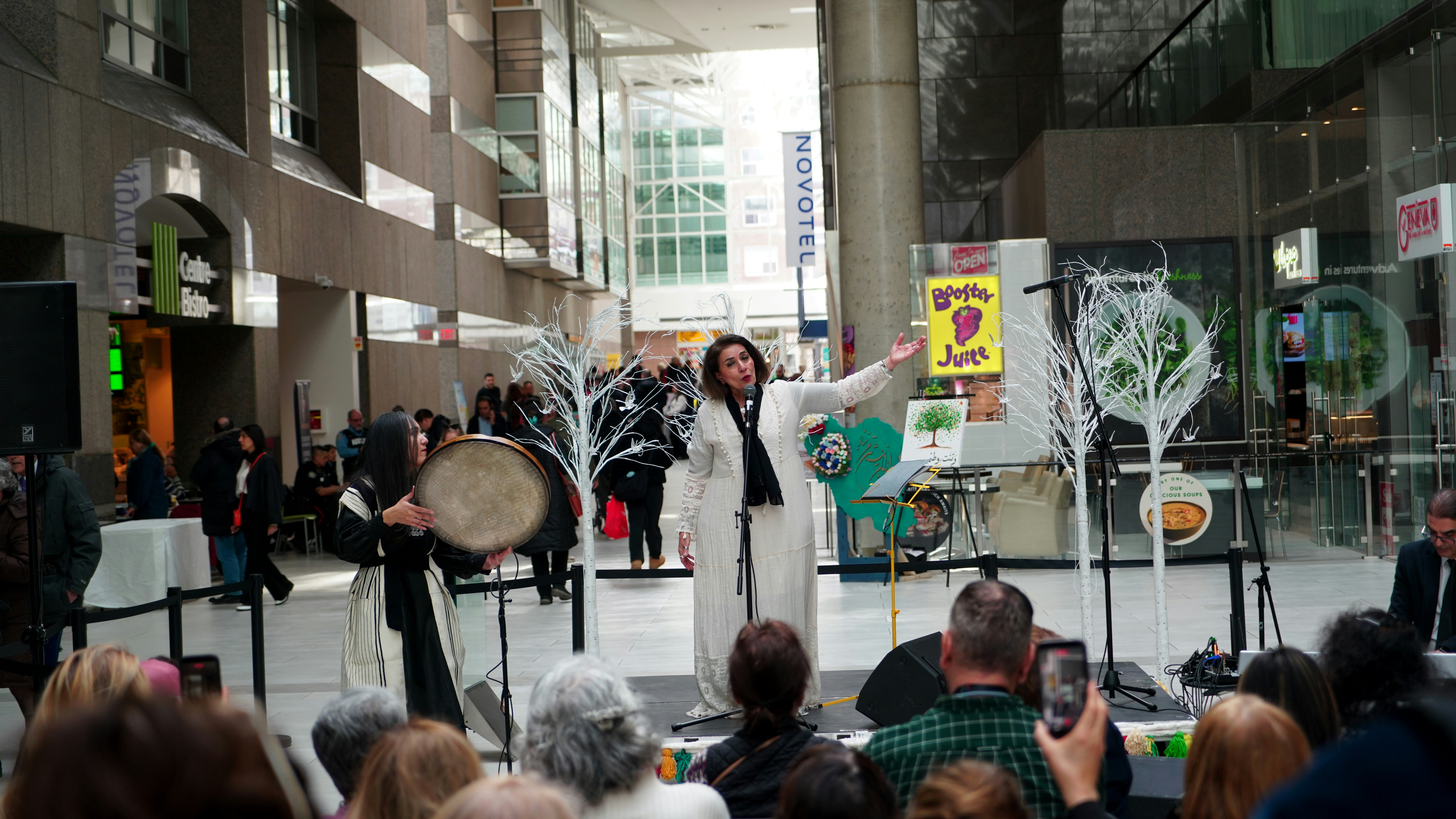 A man in a white robe performs with a drummer.