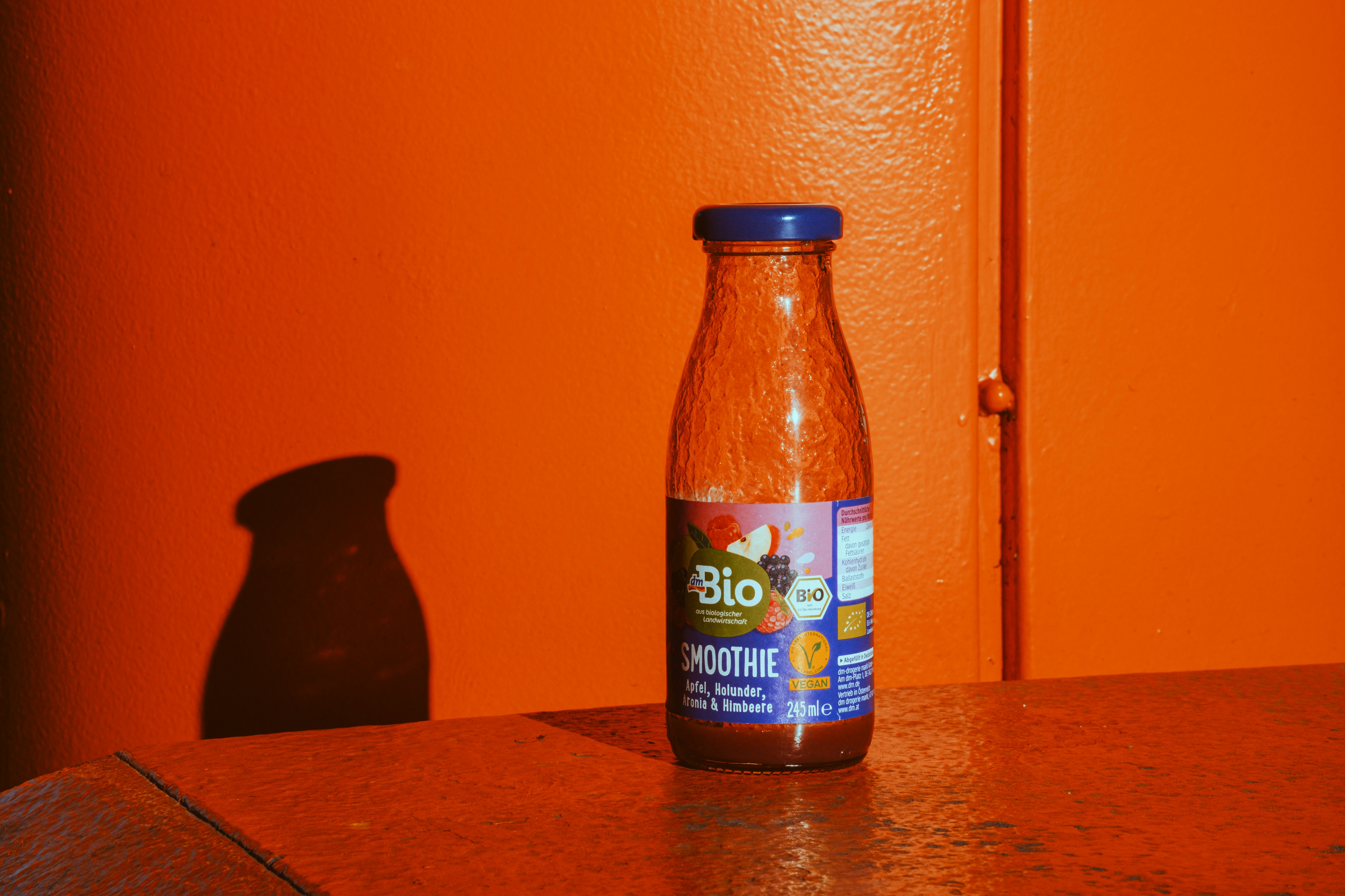 Una botella de batido bio sobre una superficie naranja.