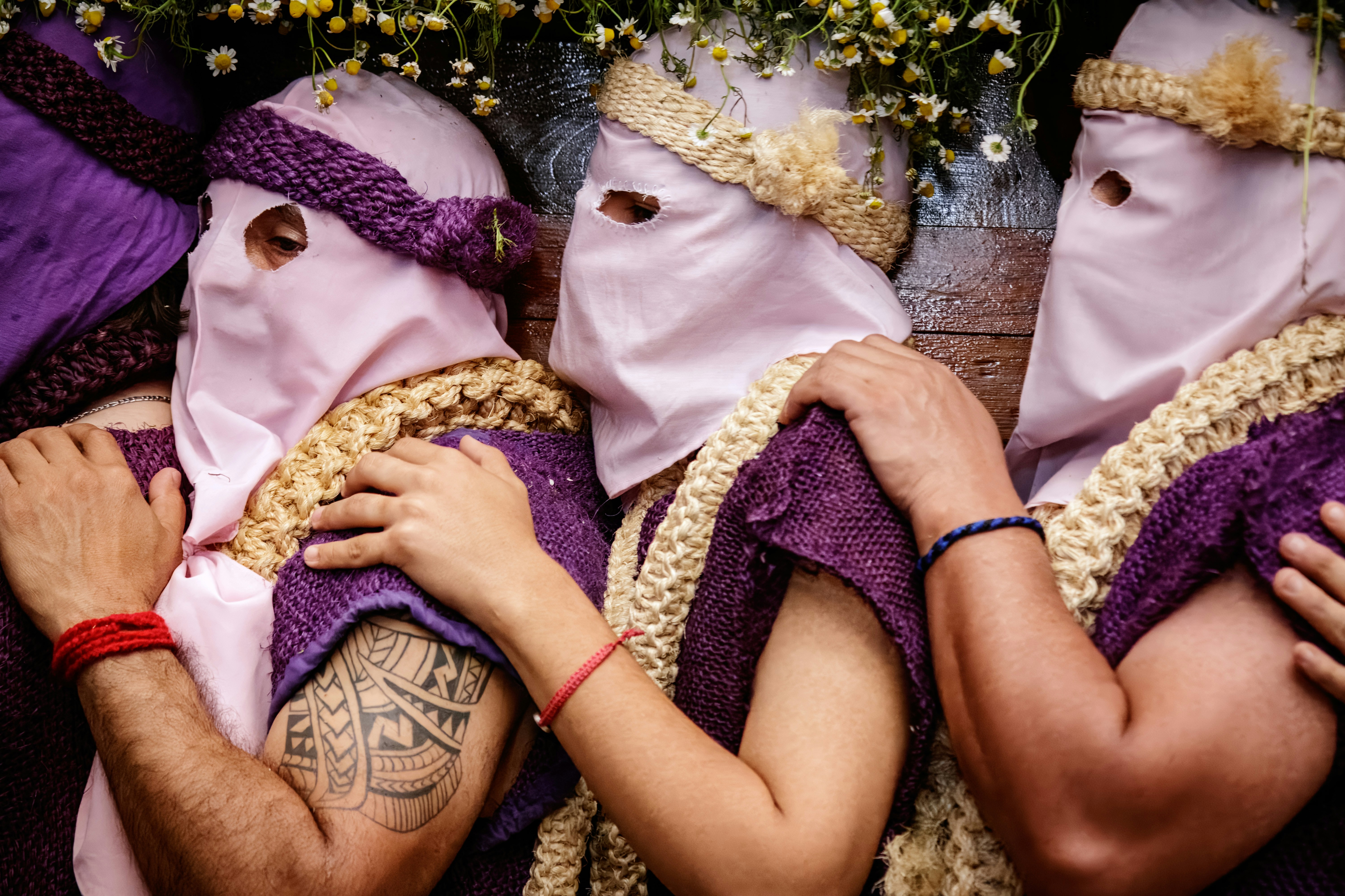 Three people in hooded robes with decorative headdresses