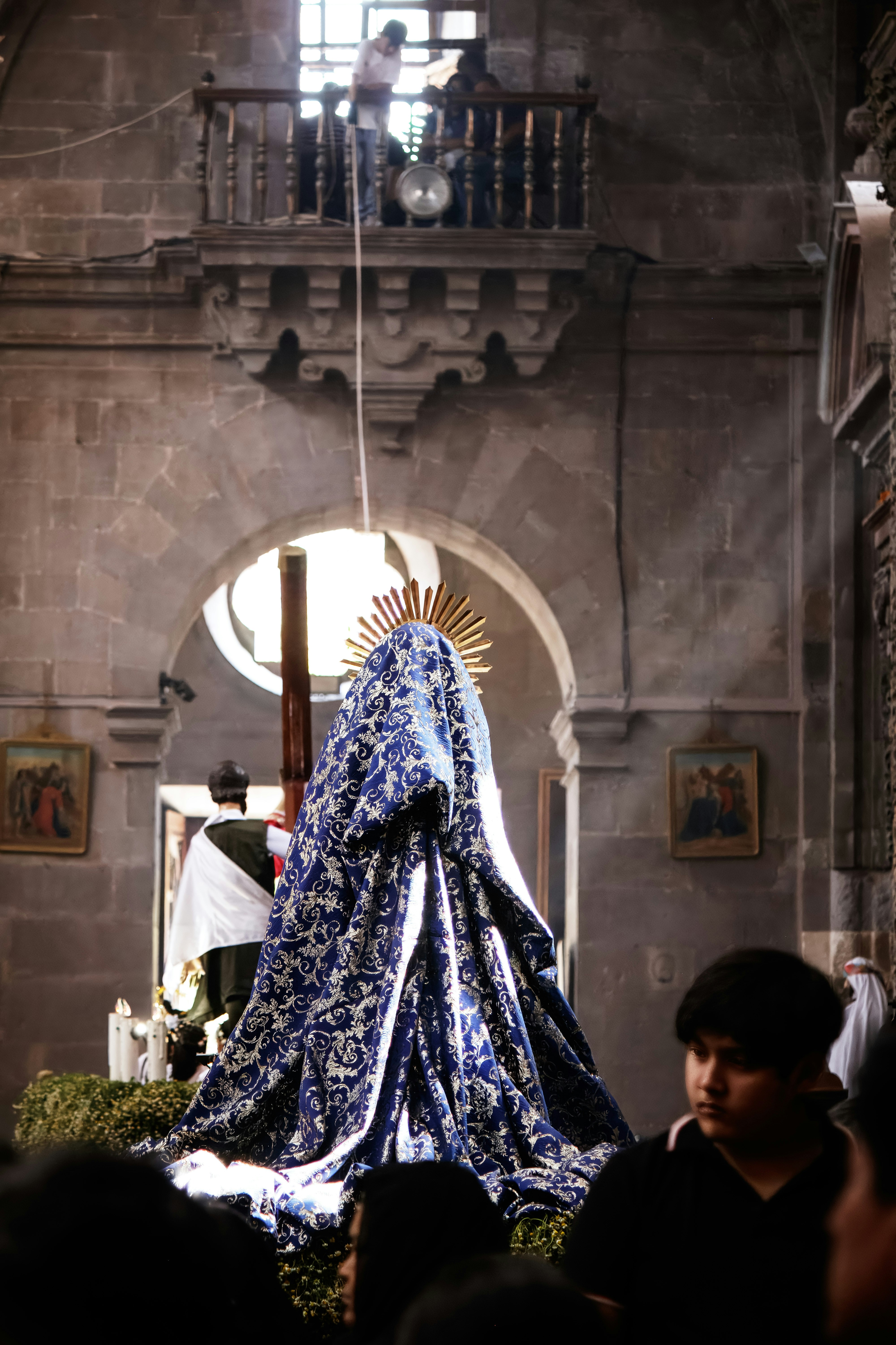 A draped statue inside a church with people watching