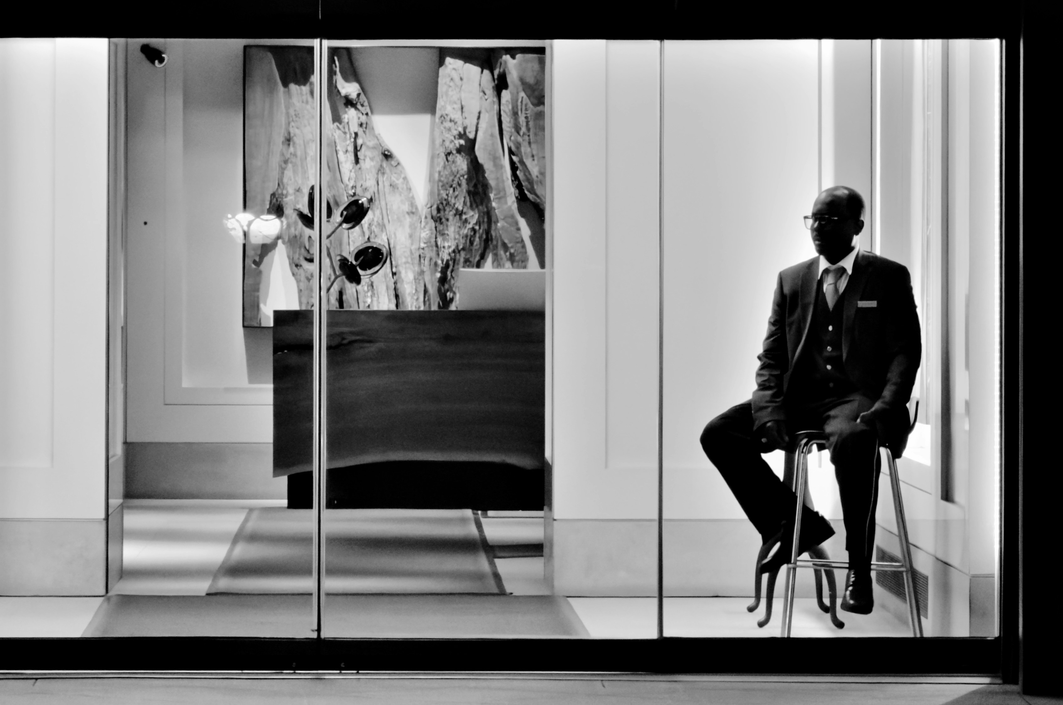 Man in suit sits in a store window display.