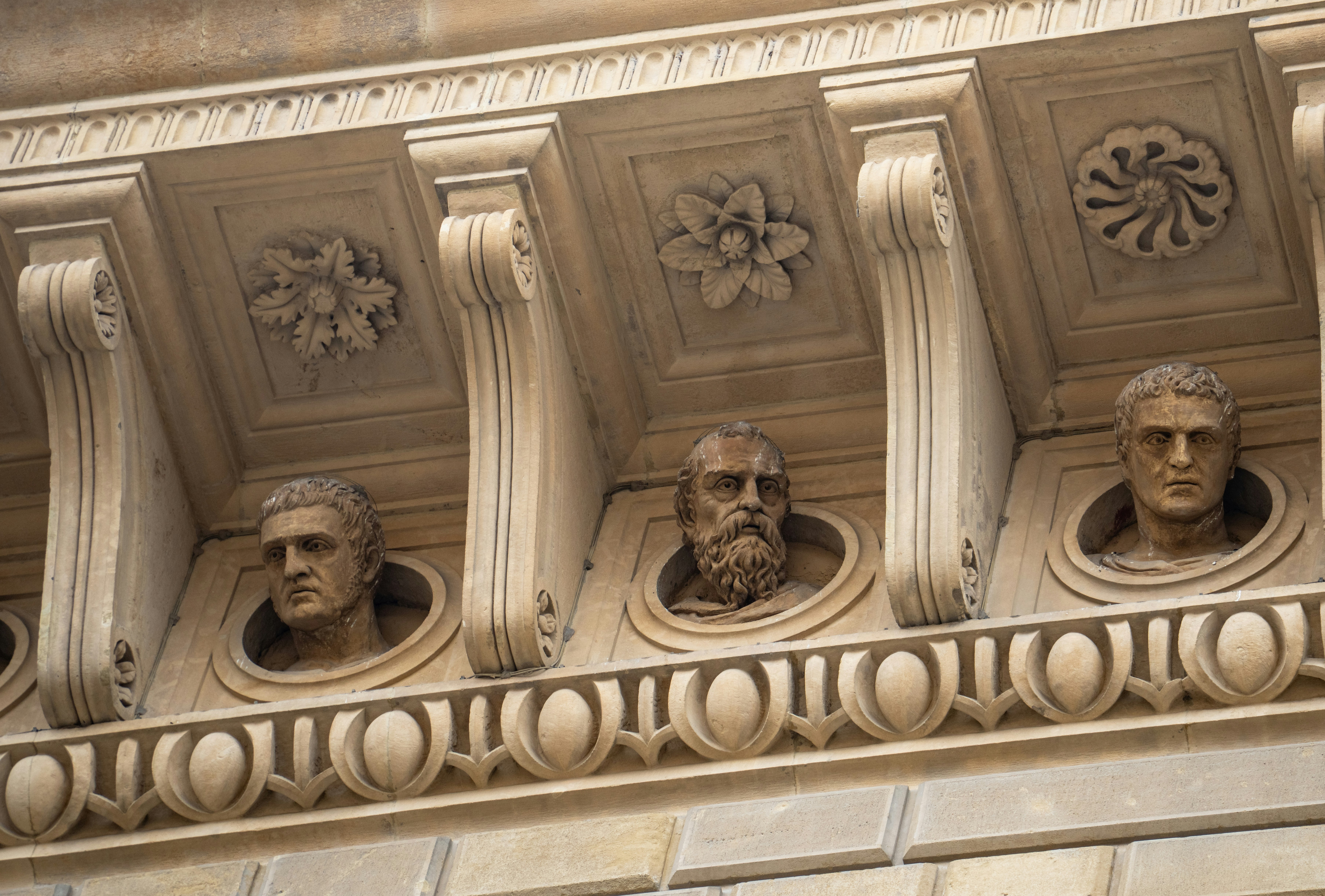 three classical busts adorn ornate building facade