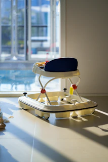 A baby walker sits by a sunlit window.