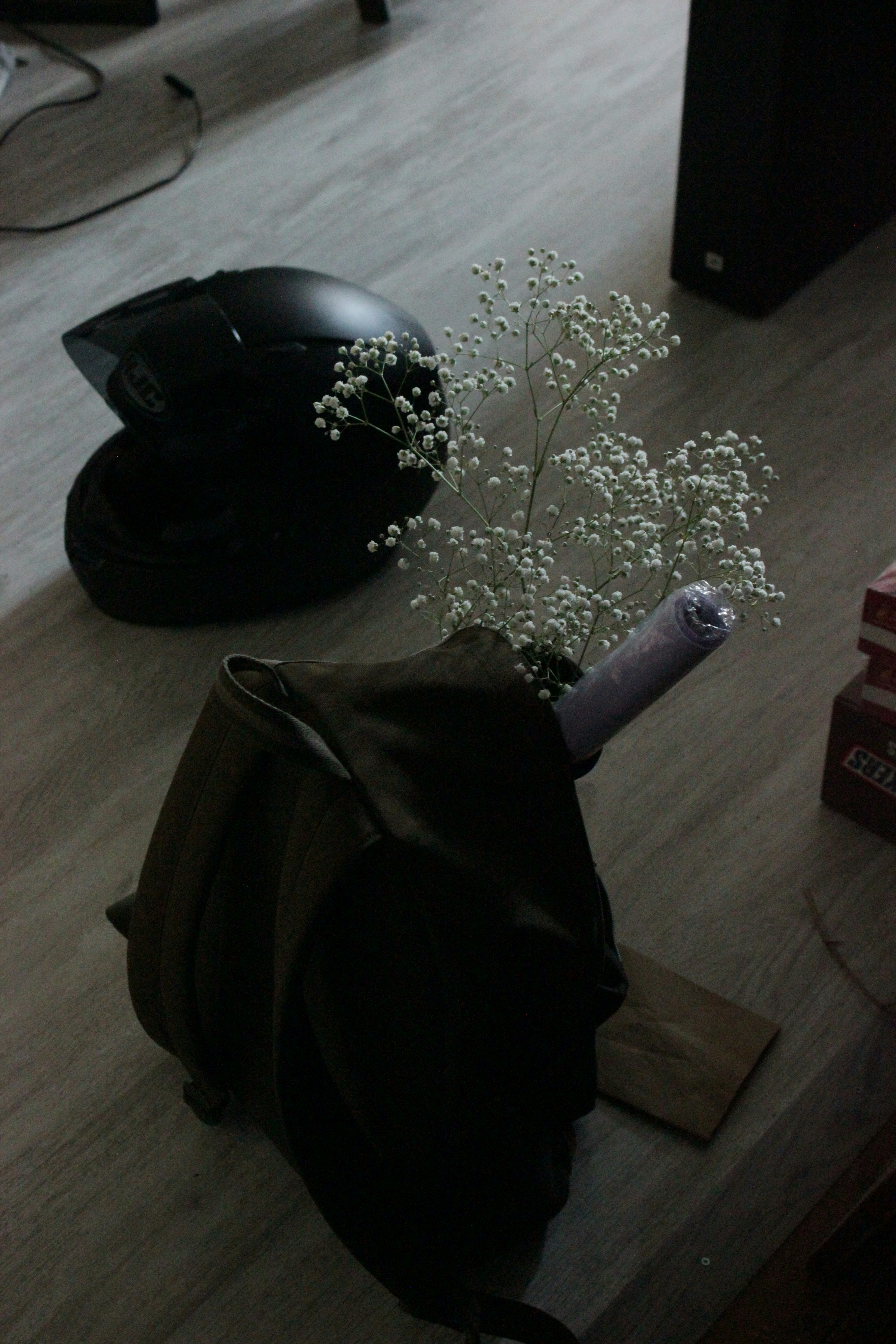 A black helmet and flowers on a wooden floor.
