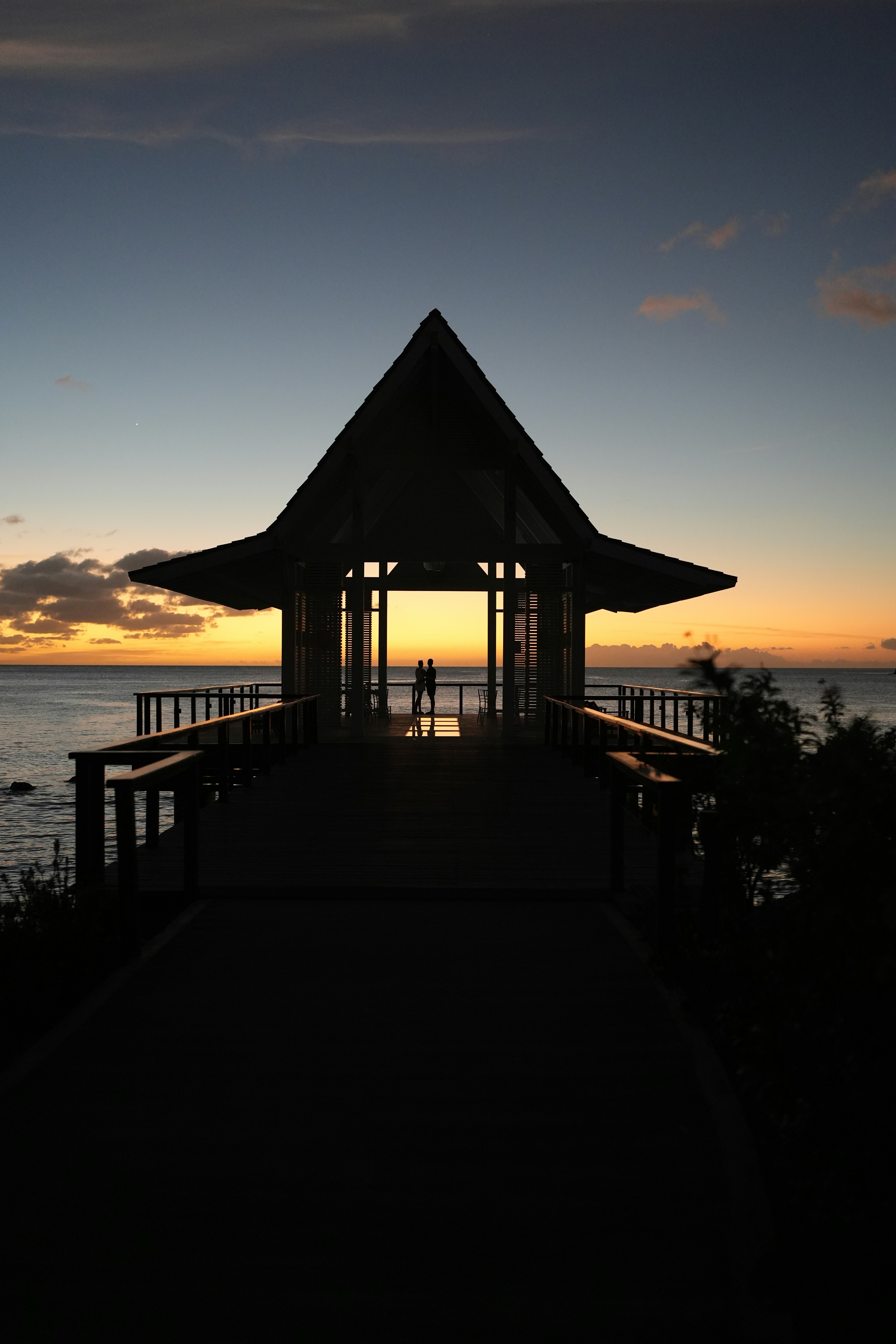 Couple en silhouette dans un kiosque surplombant l’océan au coucher de soleil