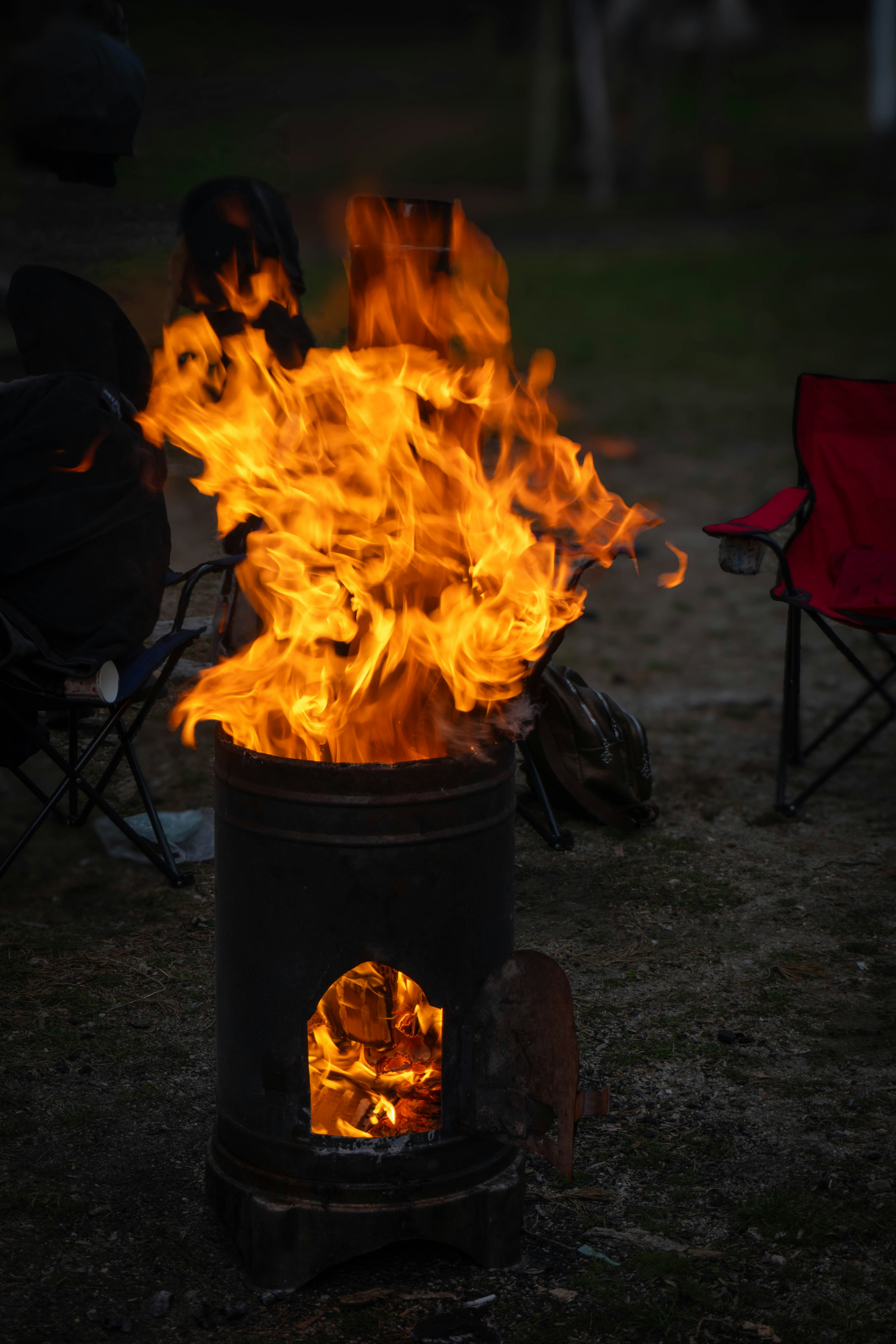 A metal barrel fire pit with flames erupting