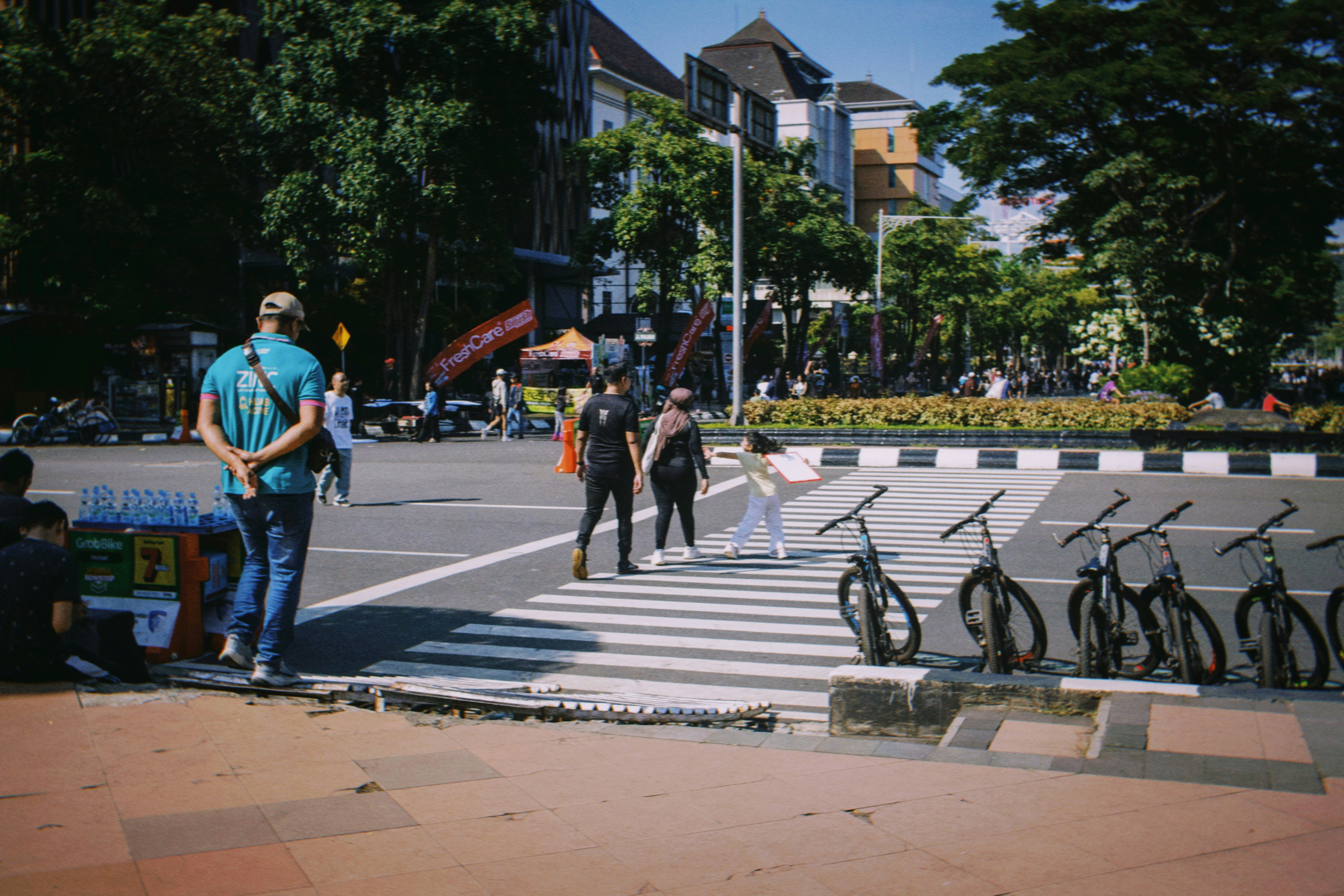 人々は横断歩道で自転車を横断し、近くに自転車が停まっています。
