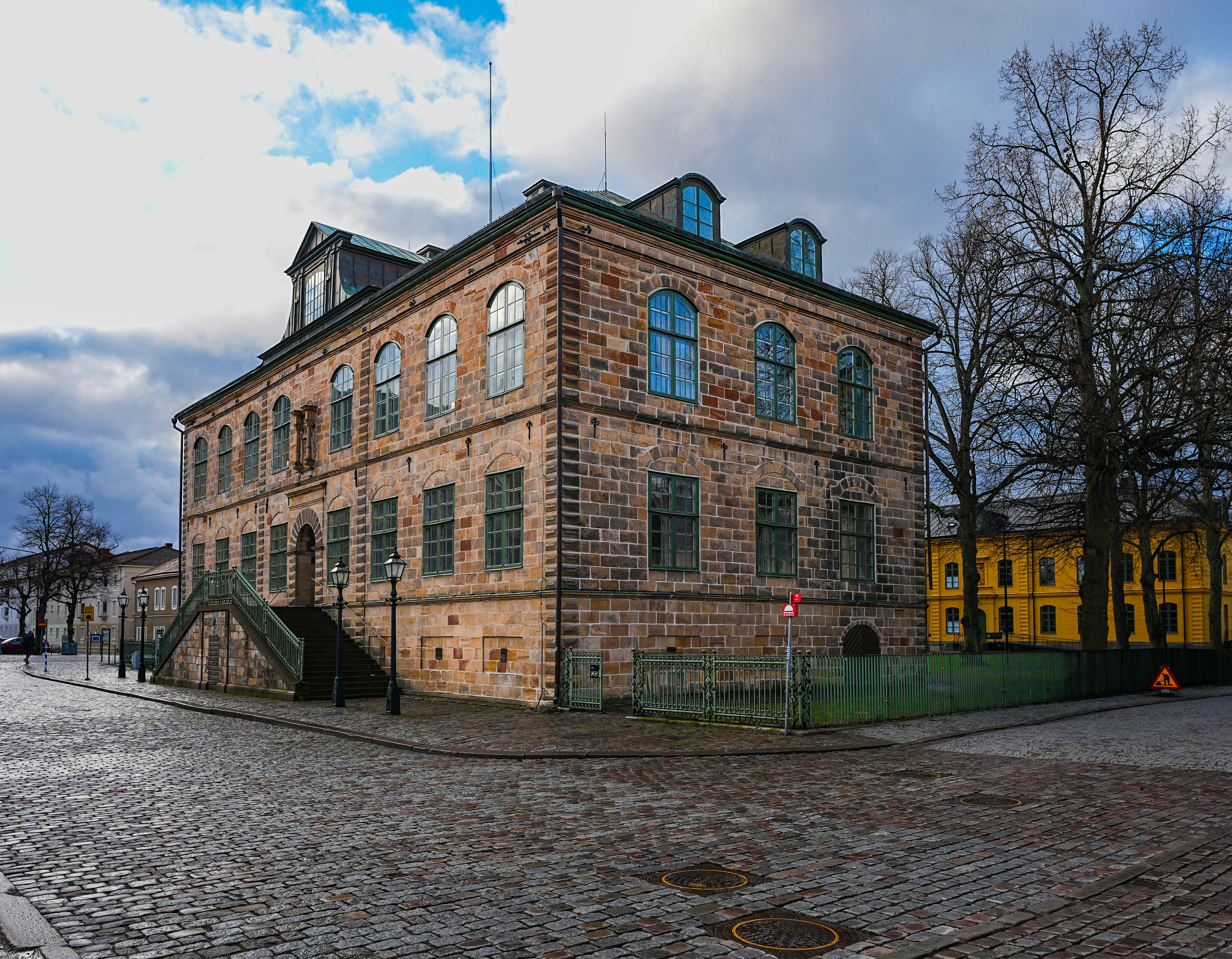 Edificio histórico de piedra con entrada arqueada y calle adoquinada.
